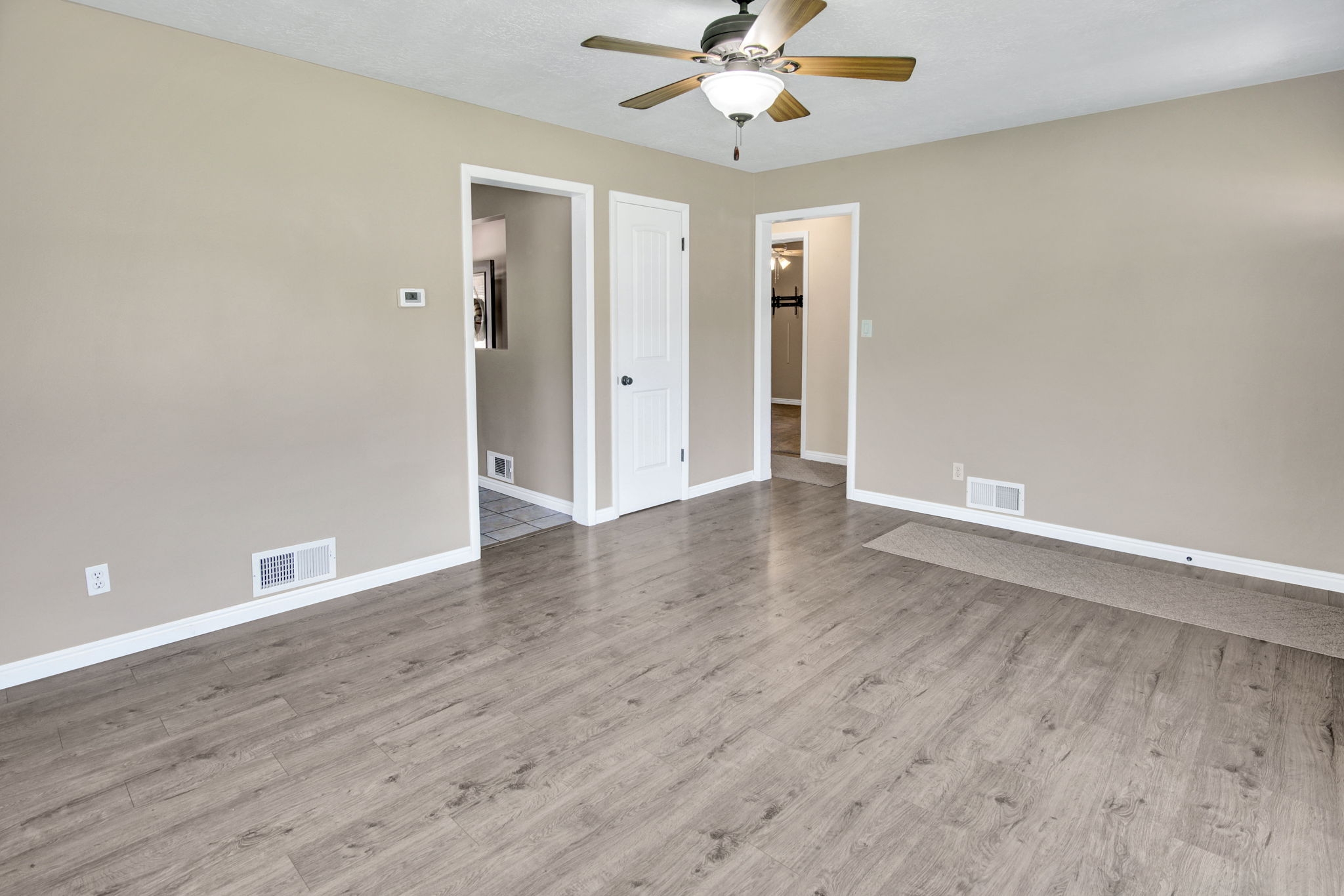 Spacious room featuring wood-finish flooring, neutral-toned walls, and white baseboards