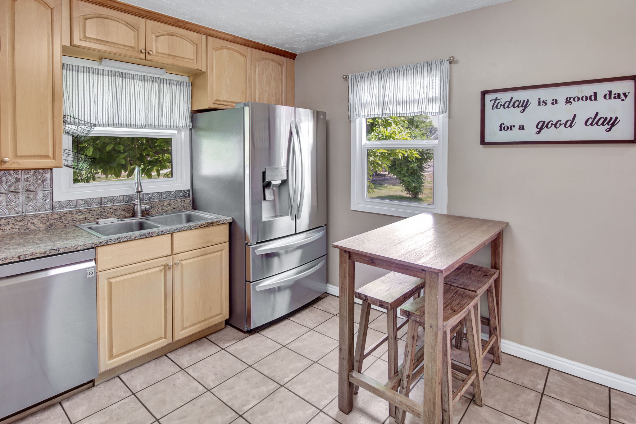 Kitchen featuring wood-finish cabinetry, stainless steel appliances, a double basin sink, and tile flooring