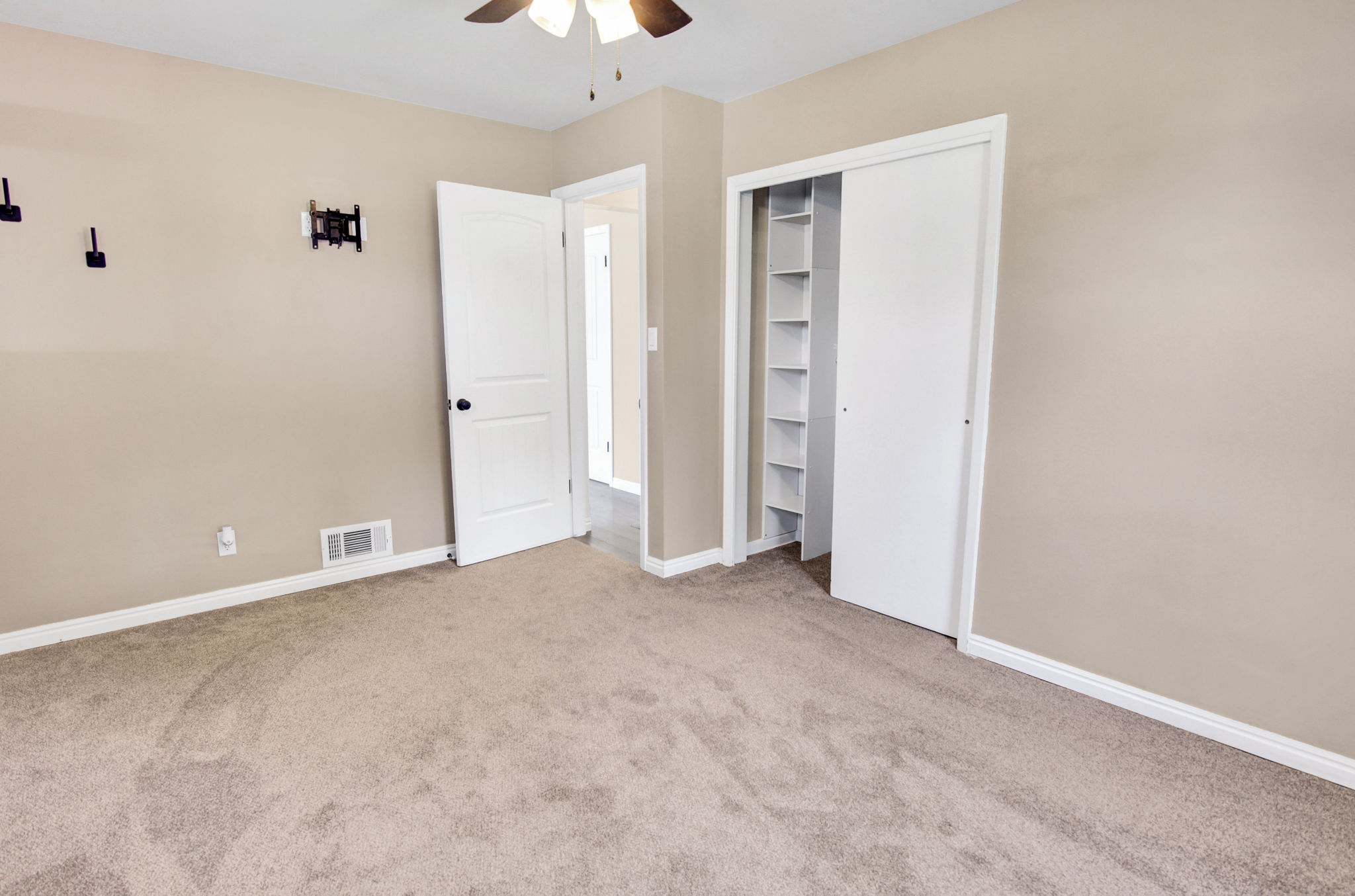 Carpeted room featuring a ceiling fan, baseboard trim, and a closet with built-in shelving