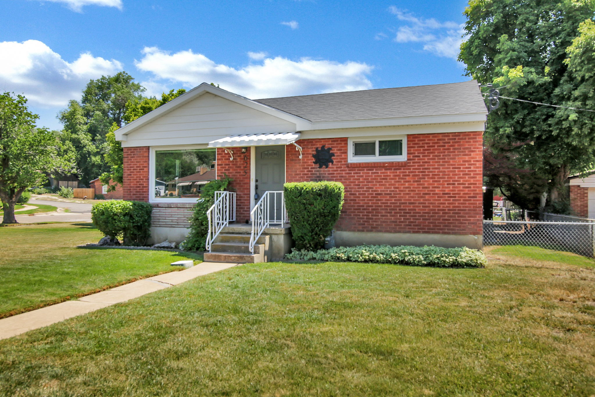 Brick exterior with white trim, featuring a front porch with white railings and a protective awning