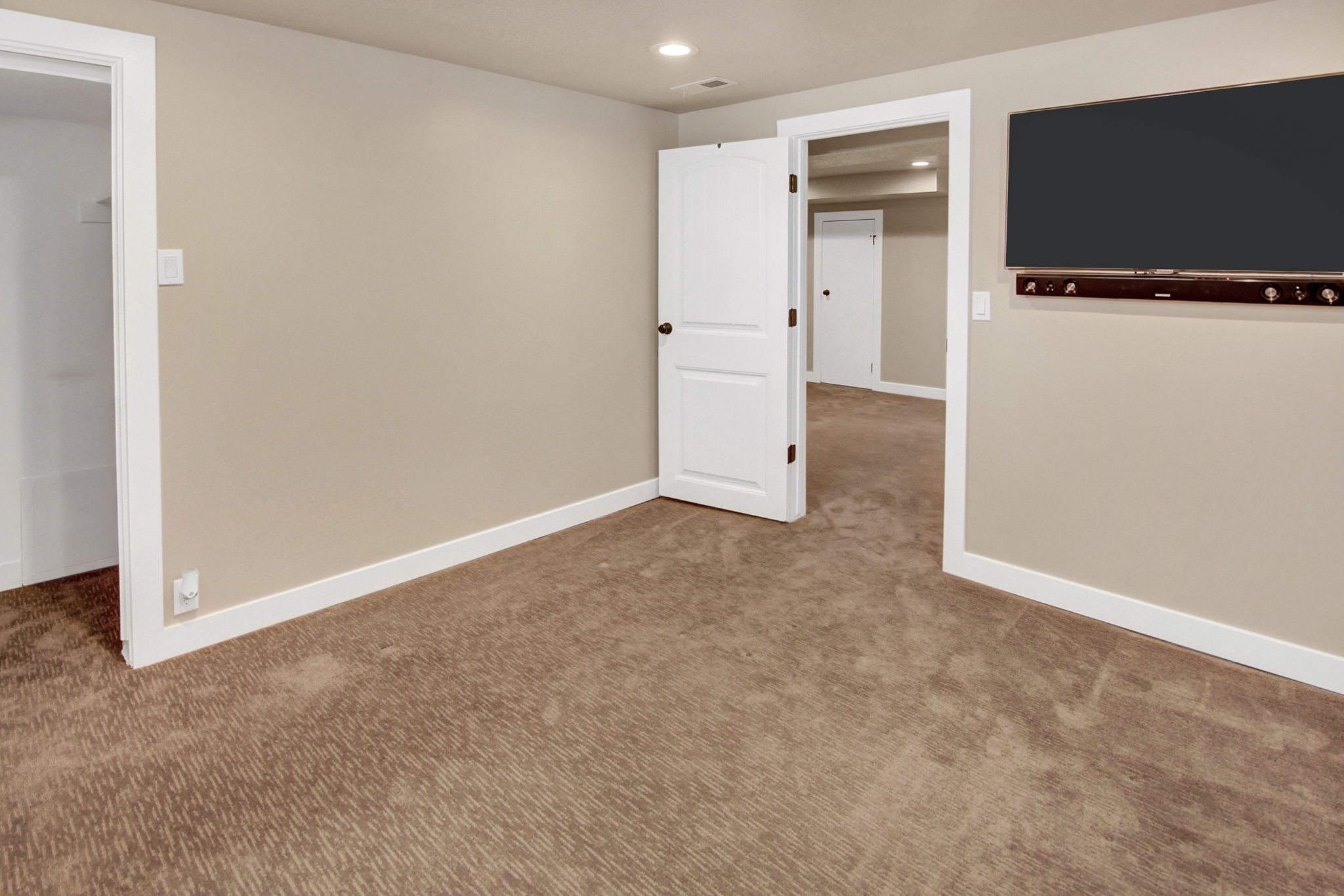 Carpeted room featuring neutral wall paint, white trim, and a wall-mounted media setup