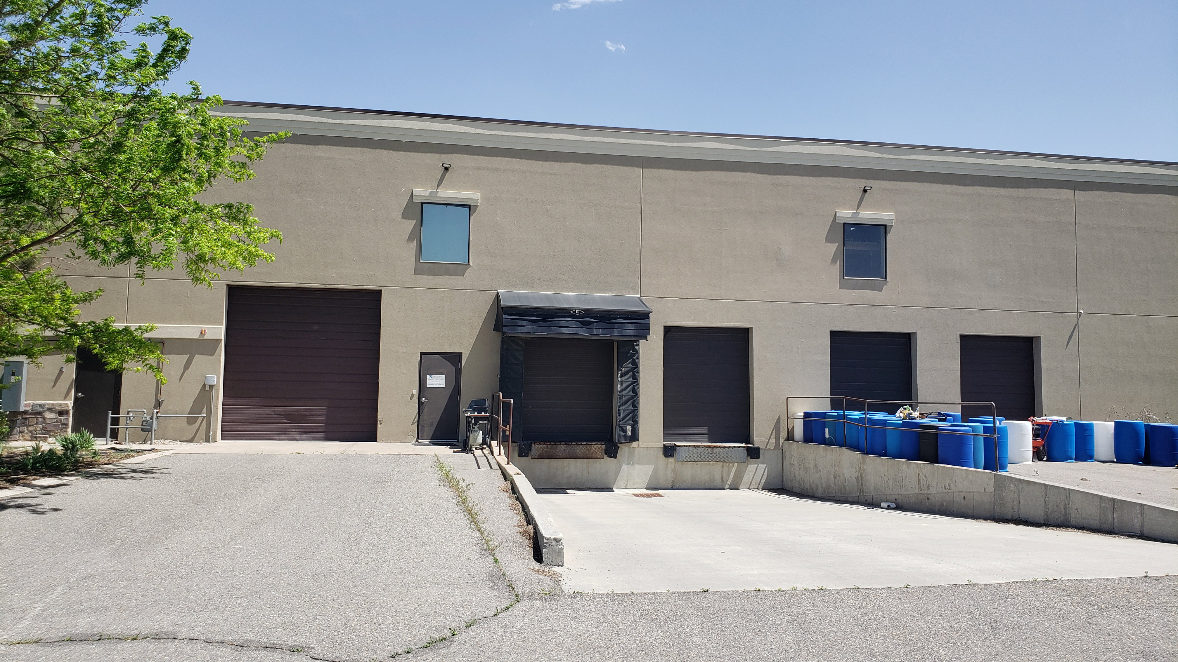 Industrial building featuring a stucco exterior, multiple loading dock doors, a large drive-in door, and an exterior personnel door