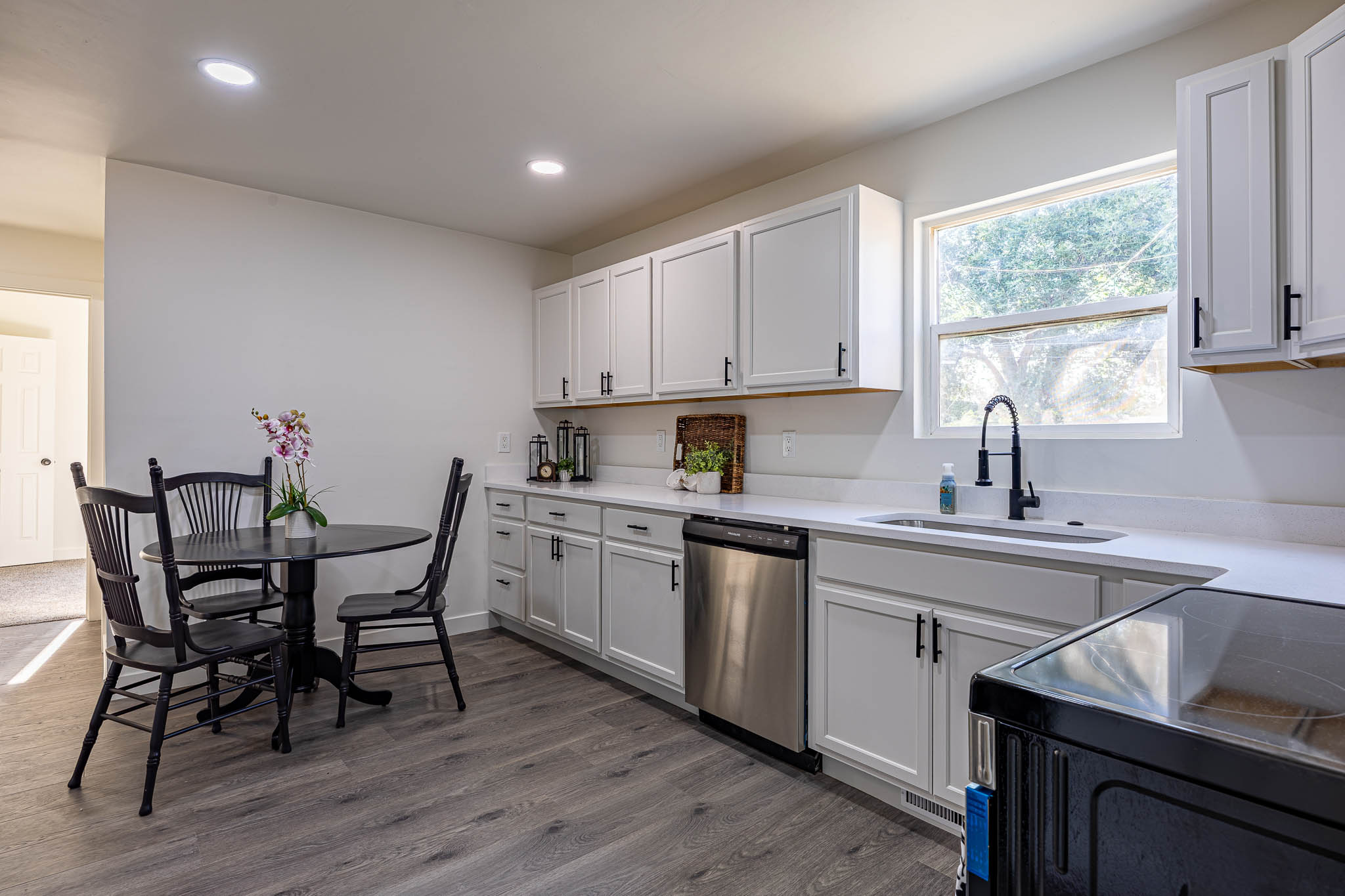 Kitchen featuring white cabinetry, light-toned countertops, and wood-finish flooring
