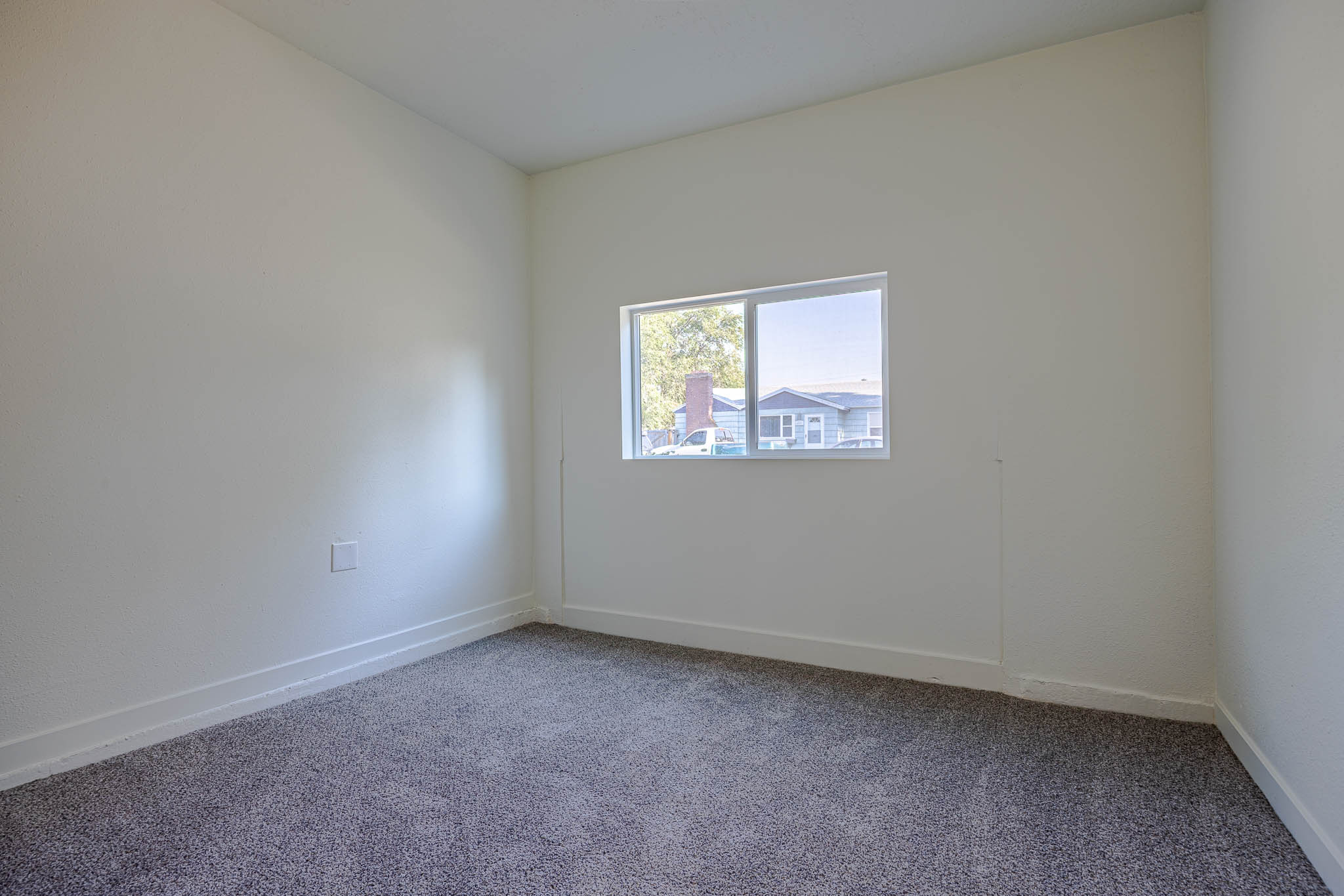 Light-filled interior space featuring neutral wall tones, white baseboards, and gray textured carpeting