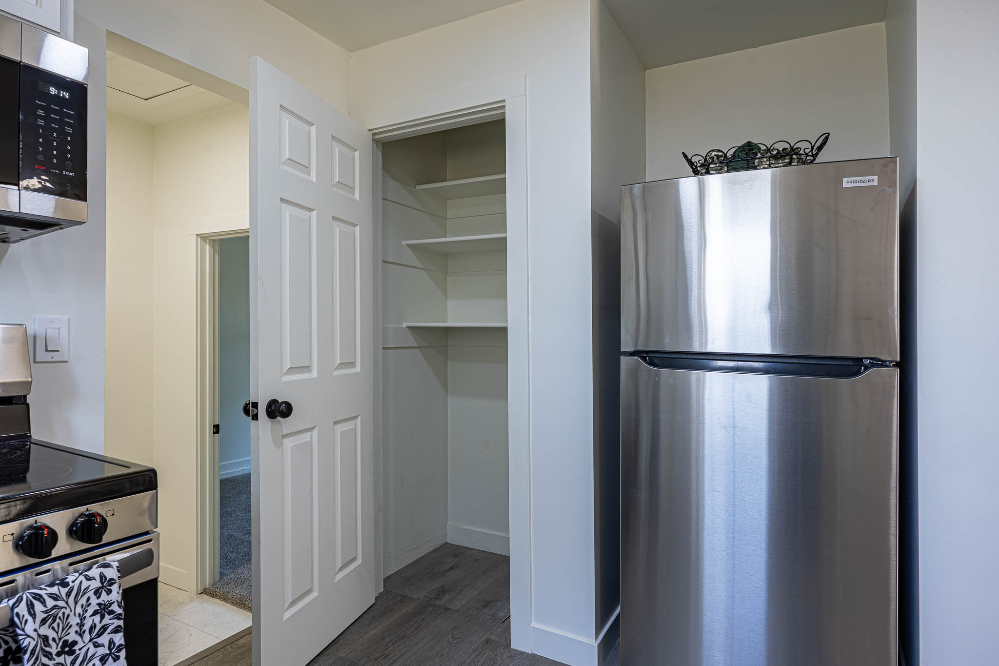 Kitchen pantry with multiple white shelves and panel door
