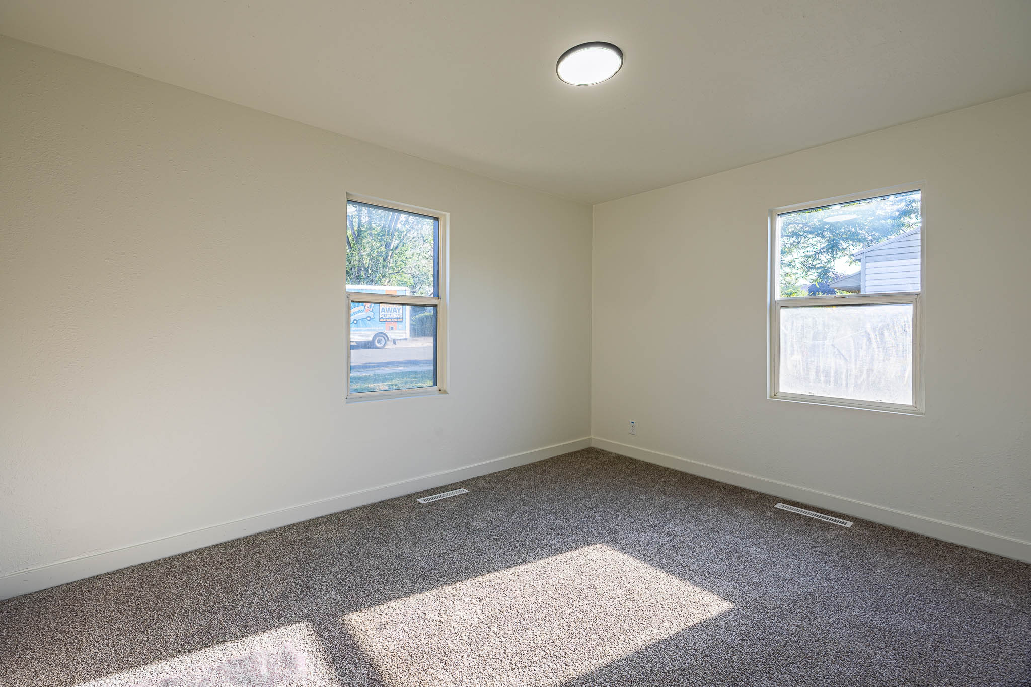 Carpeted room with two windows and a flush-mount ceiling light fixture