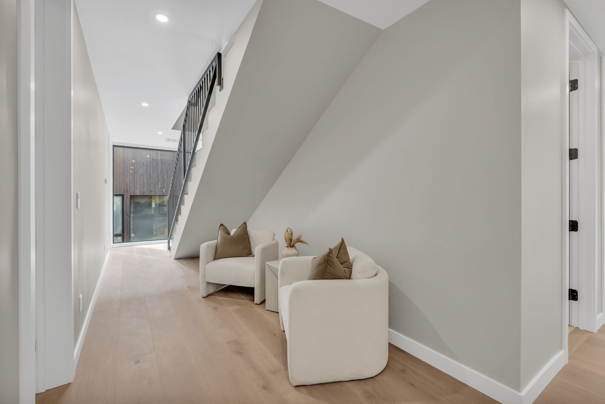 Modern staircase featuring black metal railings and light wood-finish flooring