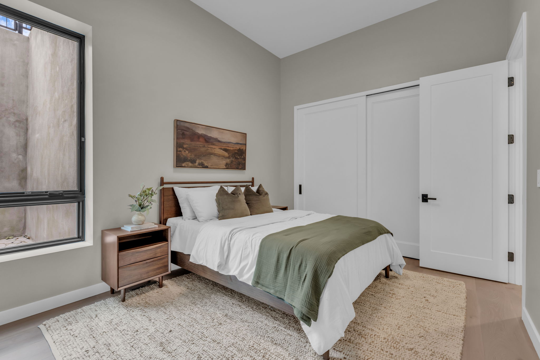 Vaulted ceiling bedroom featuring light gray walls and wood-finish flooring