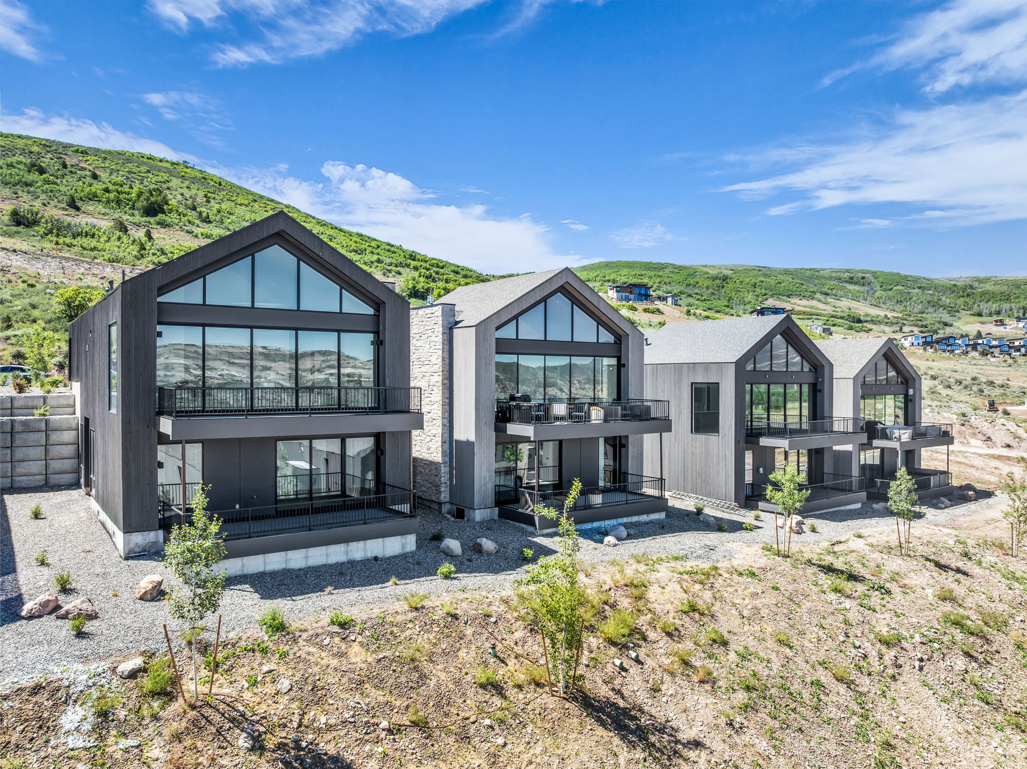 Modern gabled residences featuring dark grey siding and stone veneer accents