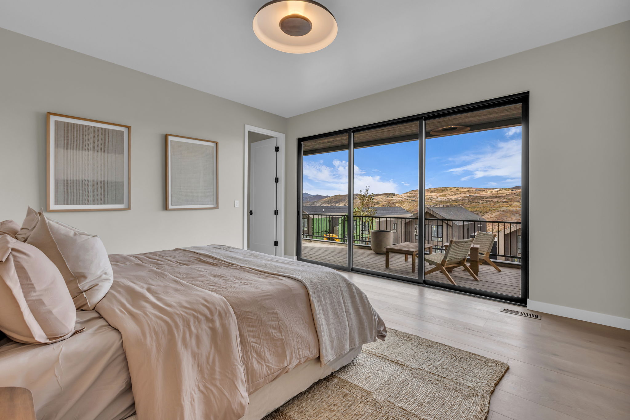 Bedroom featuring a full-wall sliding glass door, wood-finish flooring, and a contemporary ceiling light fixture