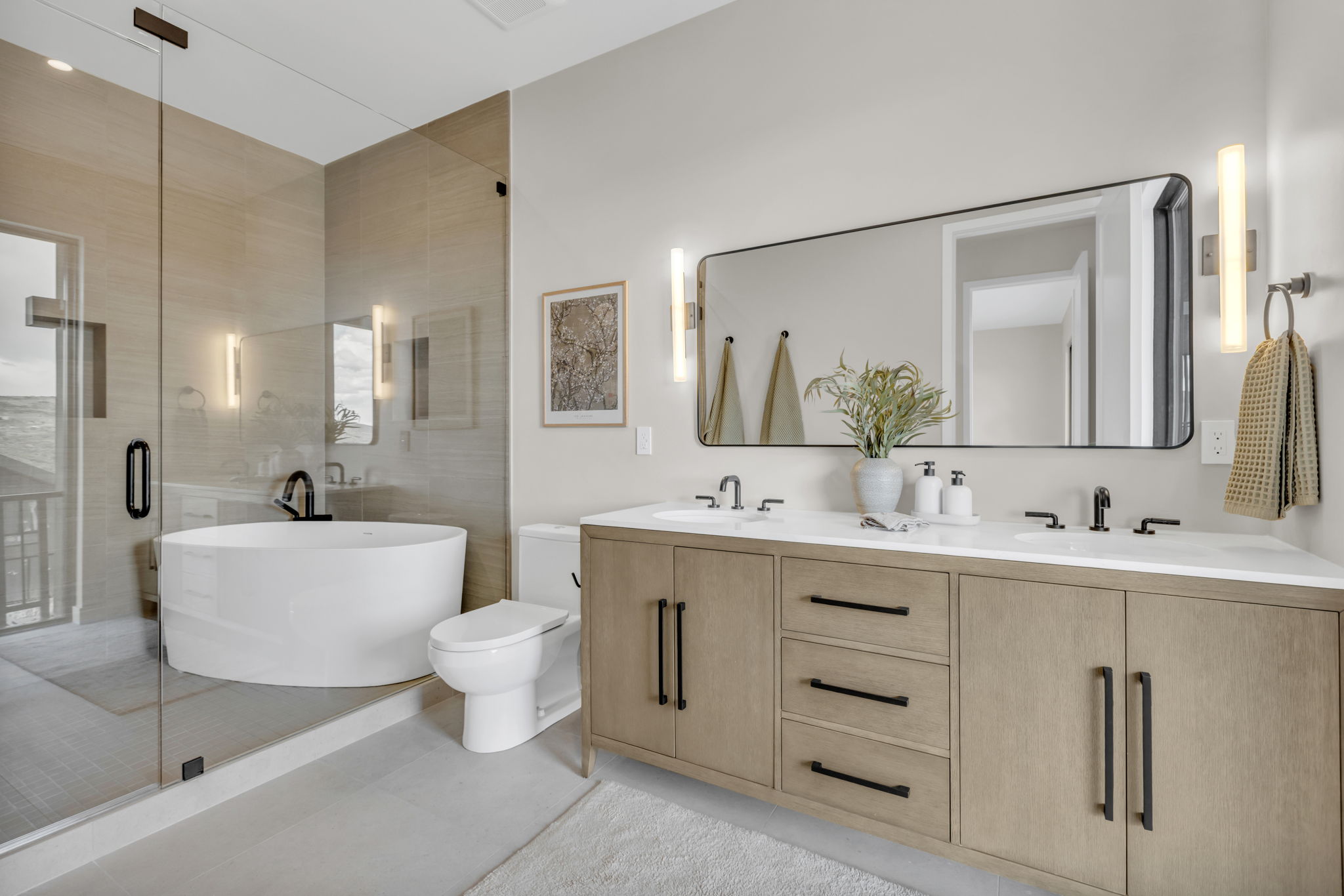 Contemporary bathroom featuring a freestanding tub, glass-enclosed shower, dual vanity with a light wood-finish, and a large rectangular mirror
