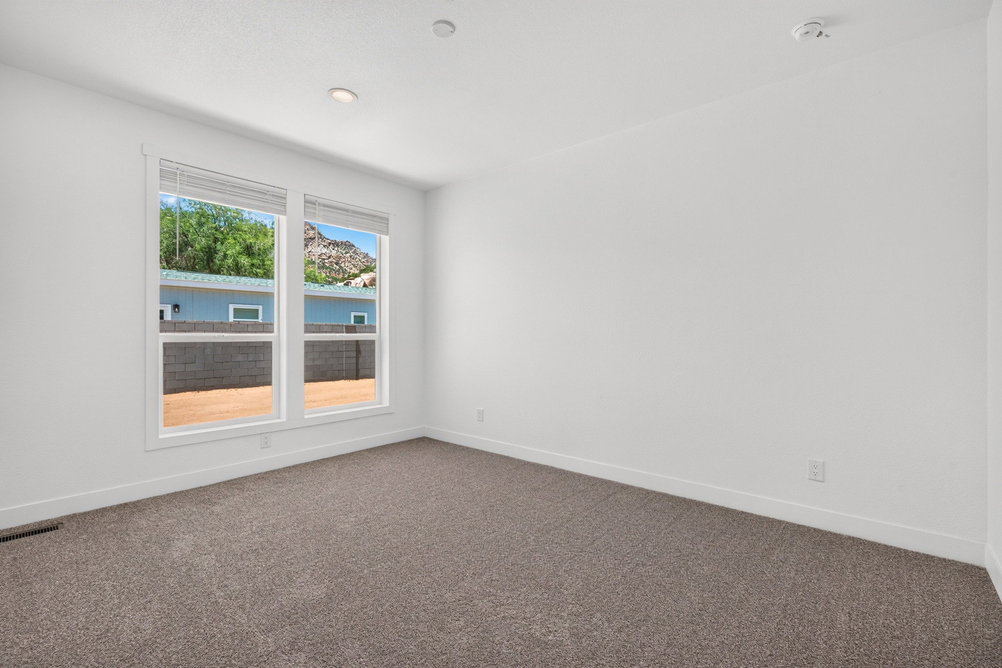 Spacious room featuring neutral carpet flooring, crisp white walls, and a large window with white trim