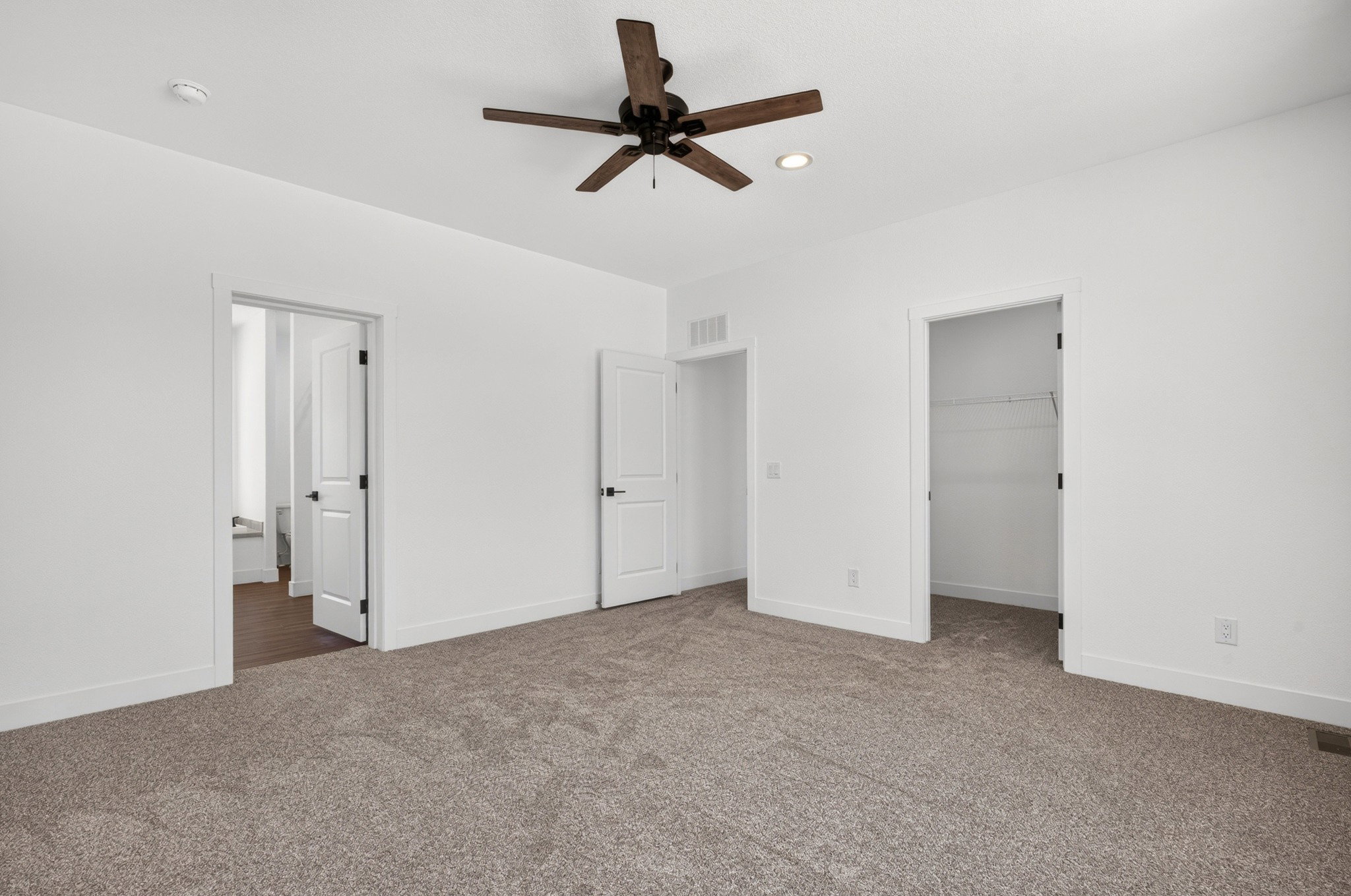 Spacious carpeted room featuring a ceiling fan with integrated lighting, recessed lighting, and multiple doorways