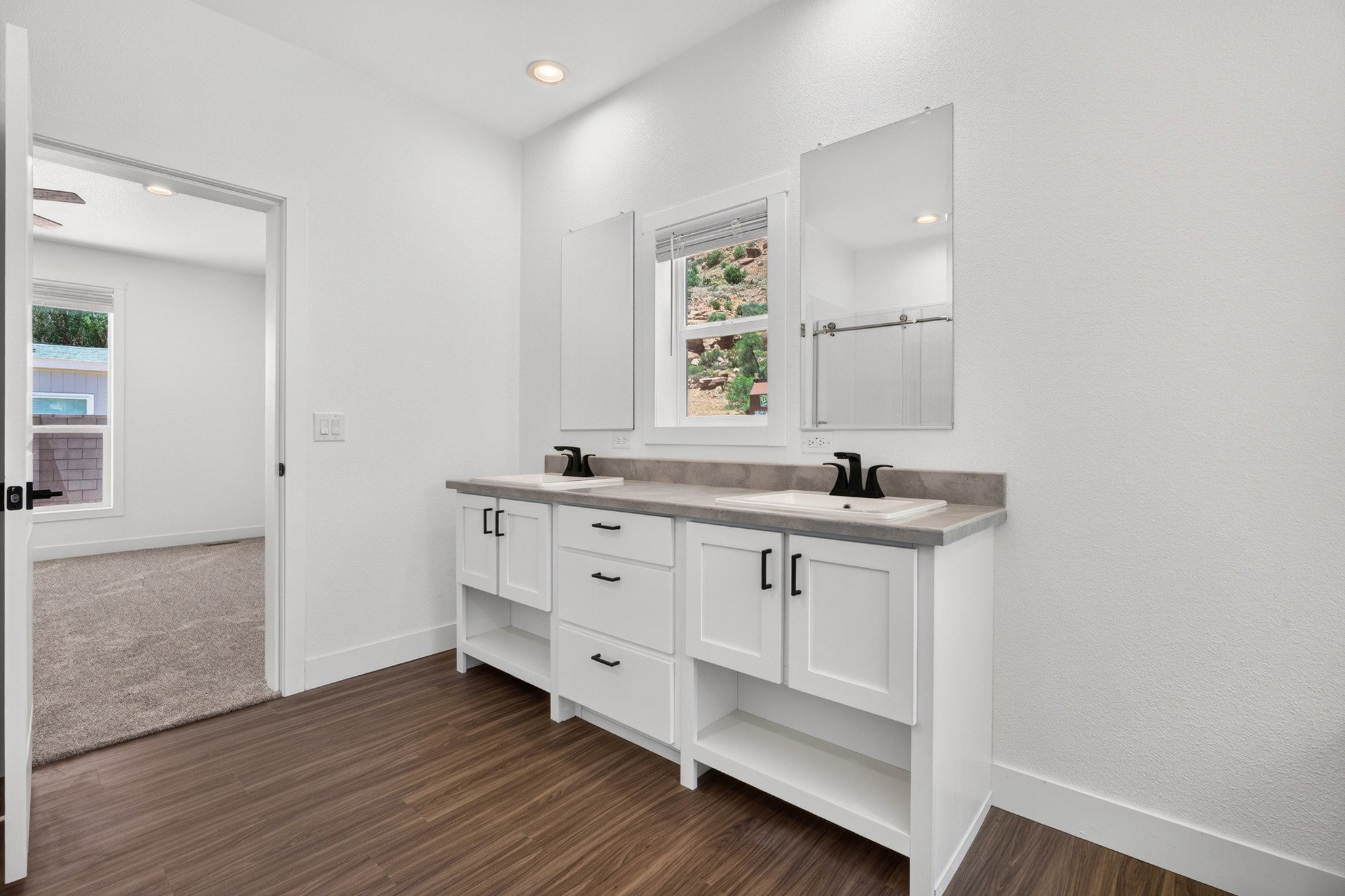 Double vanity with white cabinetry, matte black hardware, and an integrated countertop with sinks