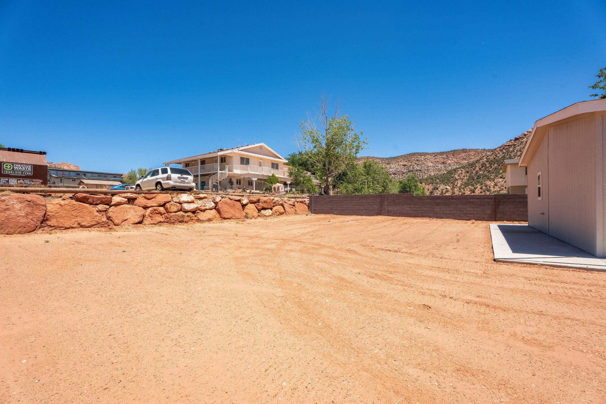Expansive graded lot featuring a concrete pad and a retaining wall constructed from natural stone