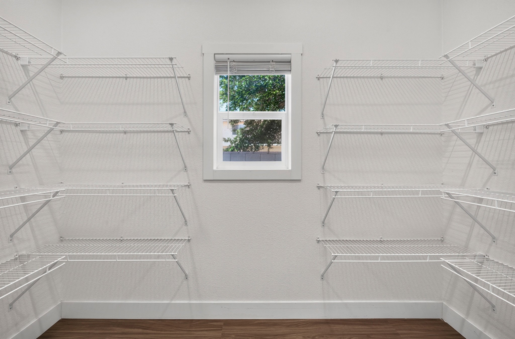 Customizable closet system featuring white wire shelving and wood-finish flooring