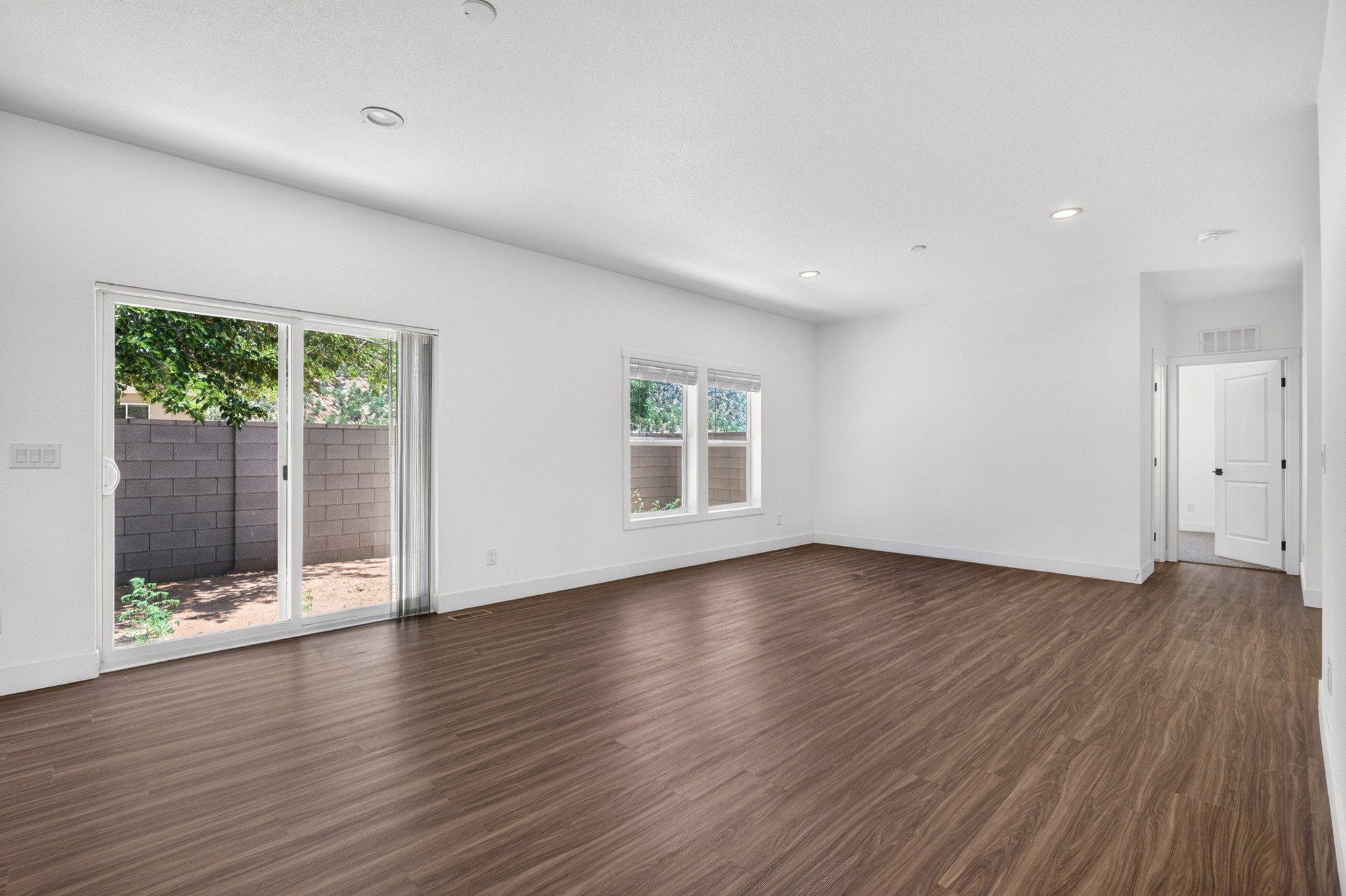 Spacious interior featuring wood-finish flooring, white walls, and recessed lighting