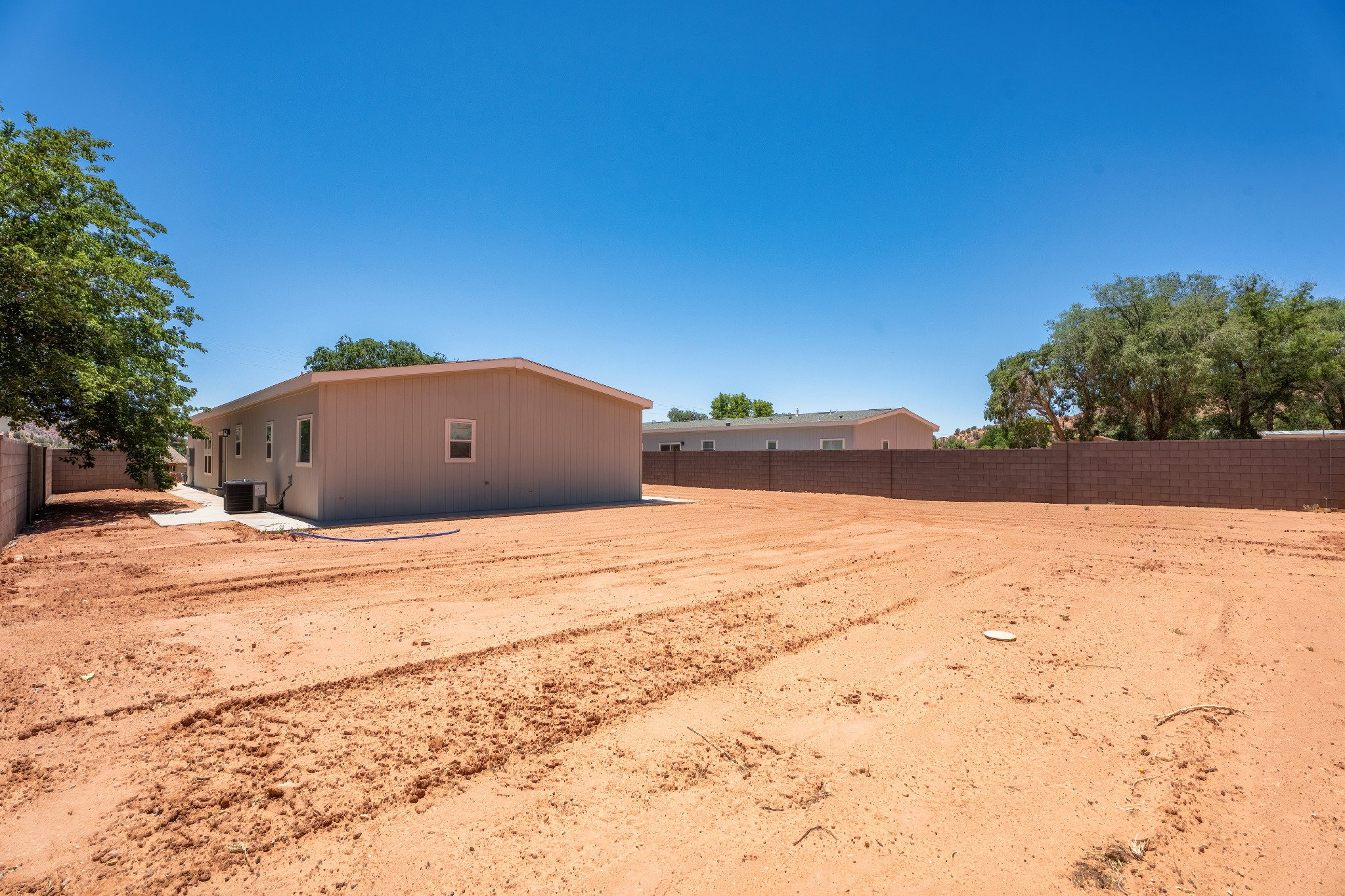 Spacious backyard with bare earth landscaping, a light beige exterior, a concrete patio, and a block perimeter fence