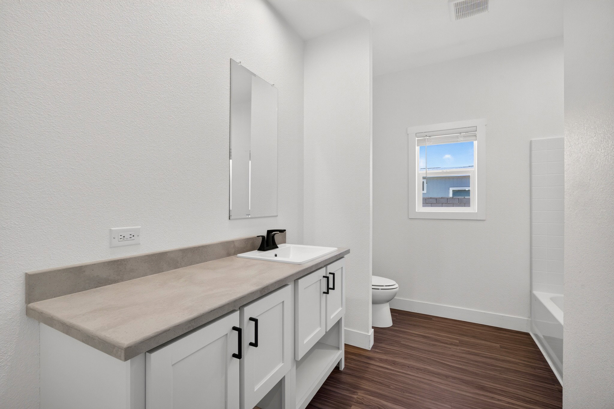 Bathroom featuring a single vanity with a white rectangular sink, matte black faucet, and a light gray countertop