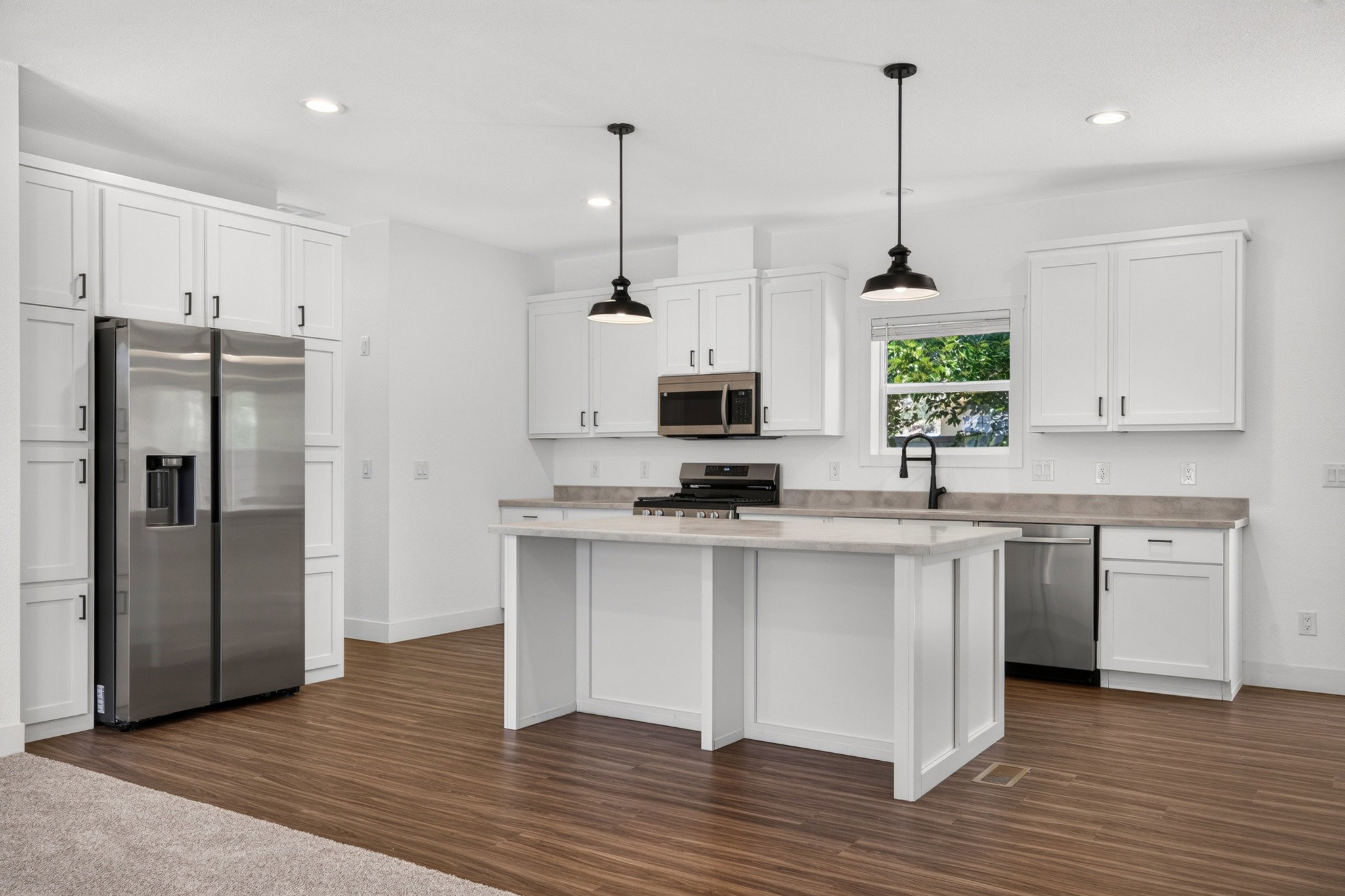 Modern kitchen featuring white shaker cabinetry, stainless steel appliances, a center island with countertop seating, and wood-finish flooring