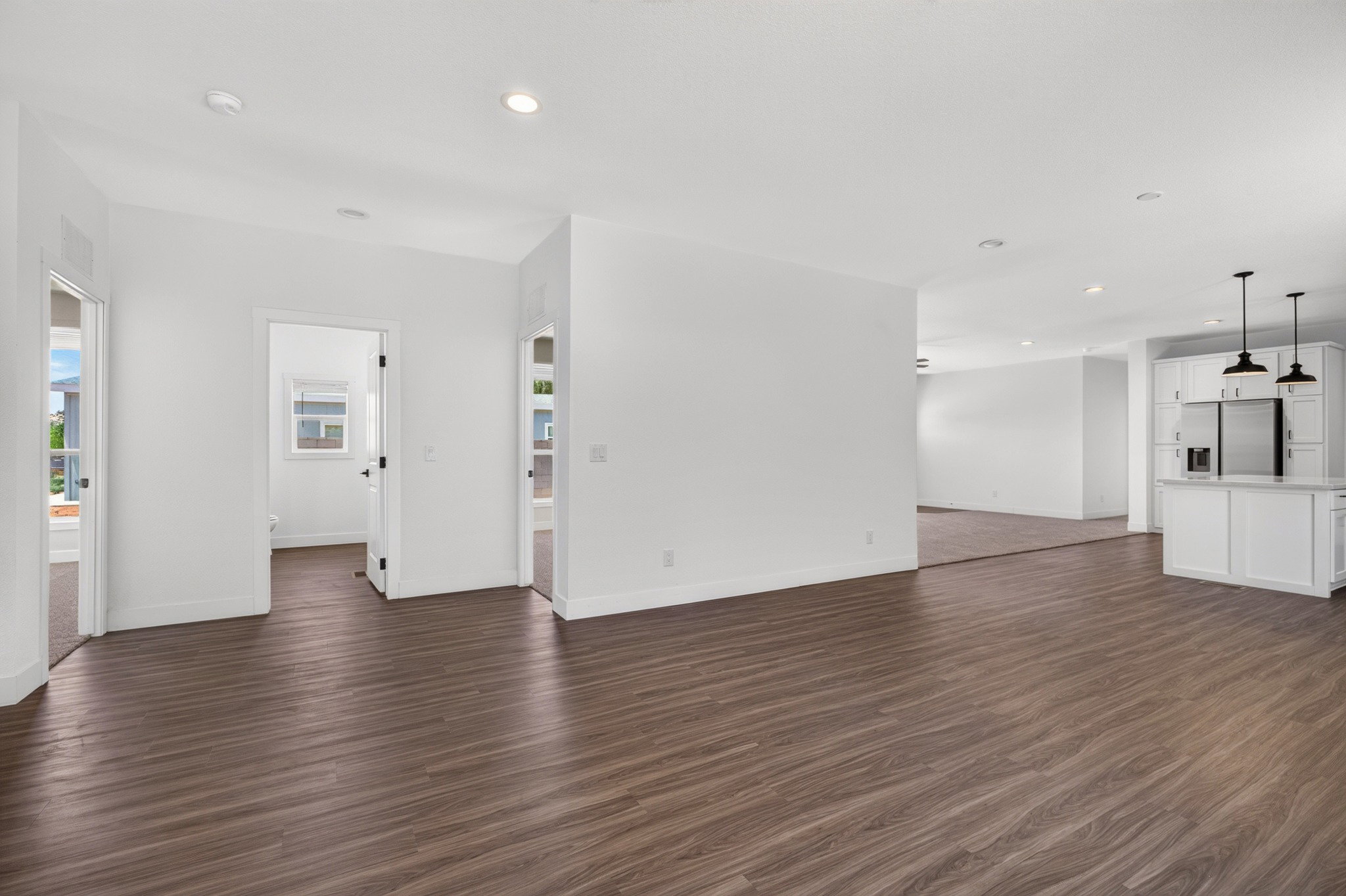 Open-concept living area featuring wood-finish flooring, recessed lighting, and a neutral color palette