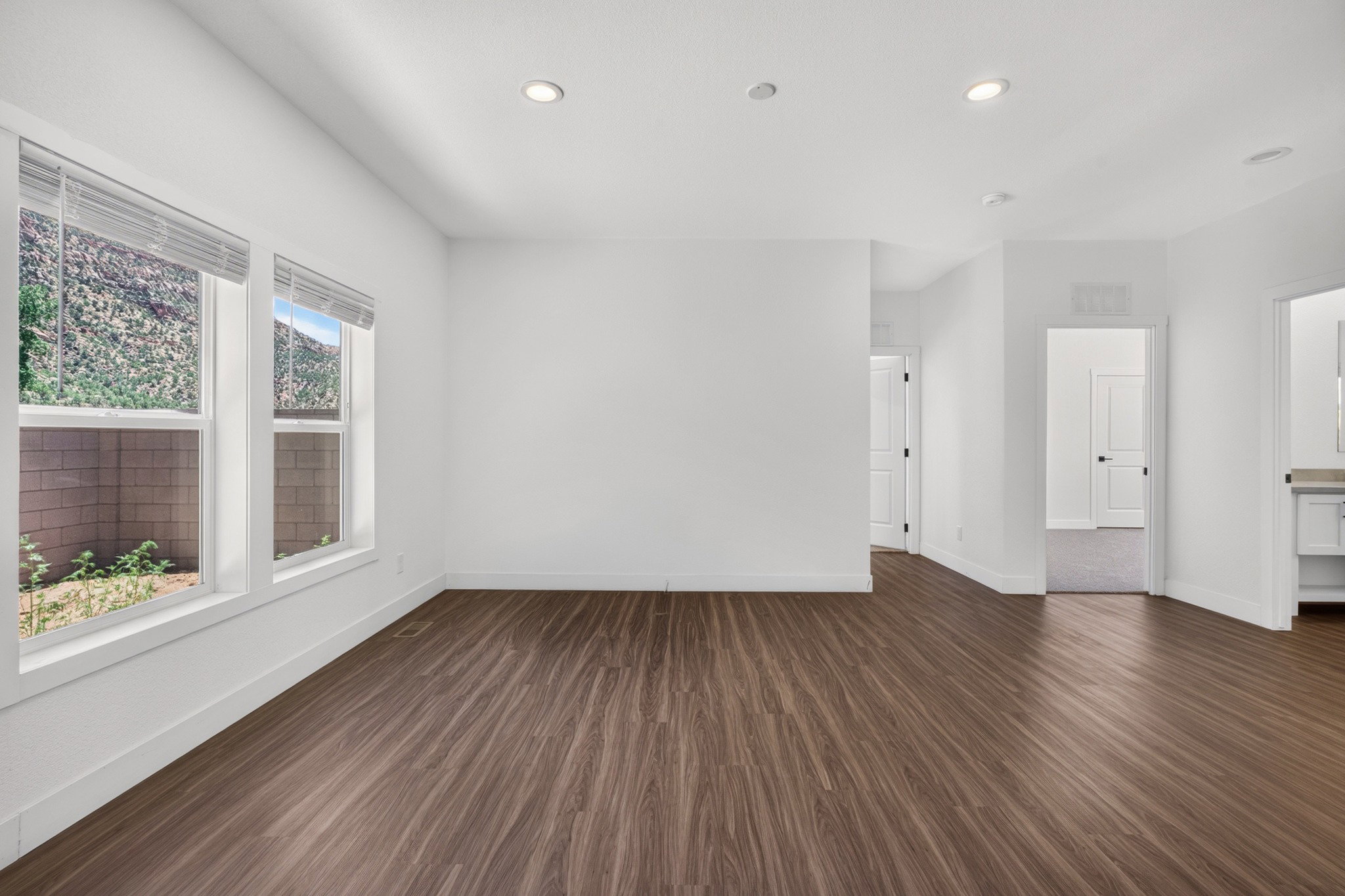 Spacious room featuring wood-finish flooring, recessed lighting, and multiple windows with blinds
