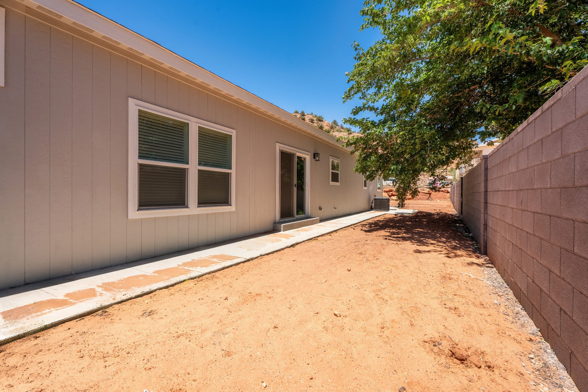 Side exterior featuring vertical panel siding, multiple windows, and a sliding glass door