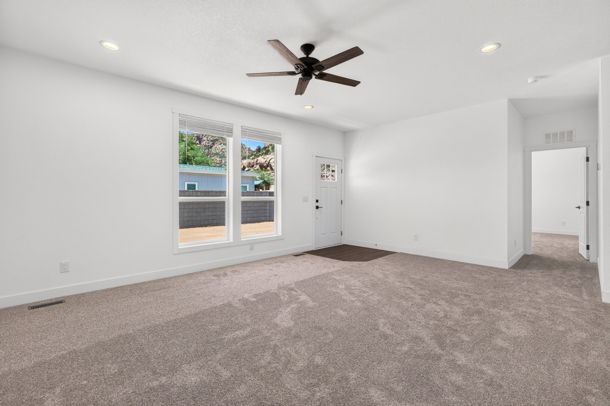 Spacious room featuring new carpet flooring, recessed lighting, and a dark-toned ceiling fan