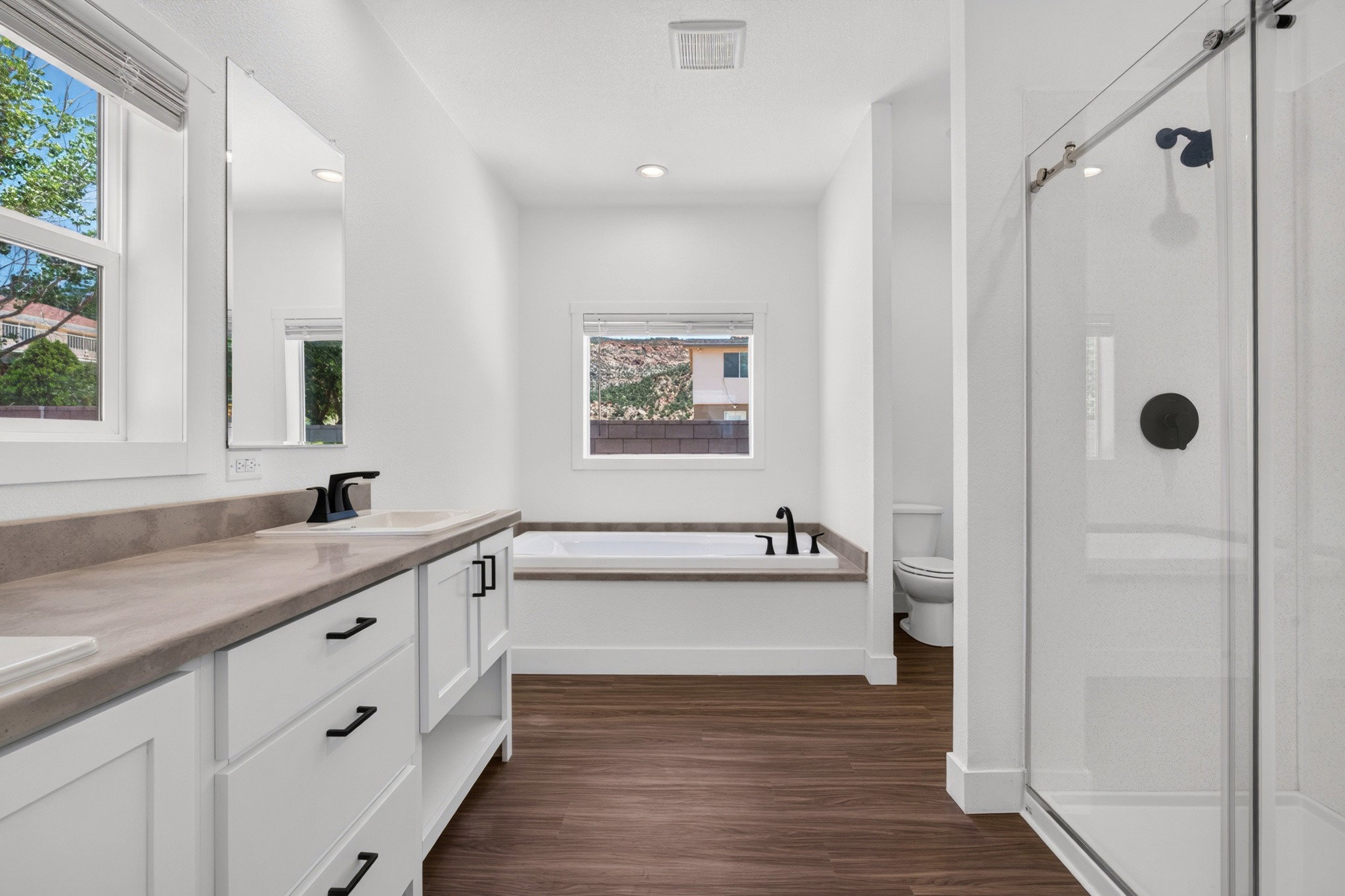 Bathroom featuring a dual vanity with a light-toned countertop, white cabinetry, and matte black hardware