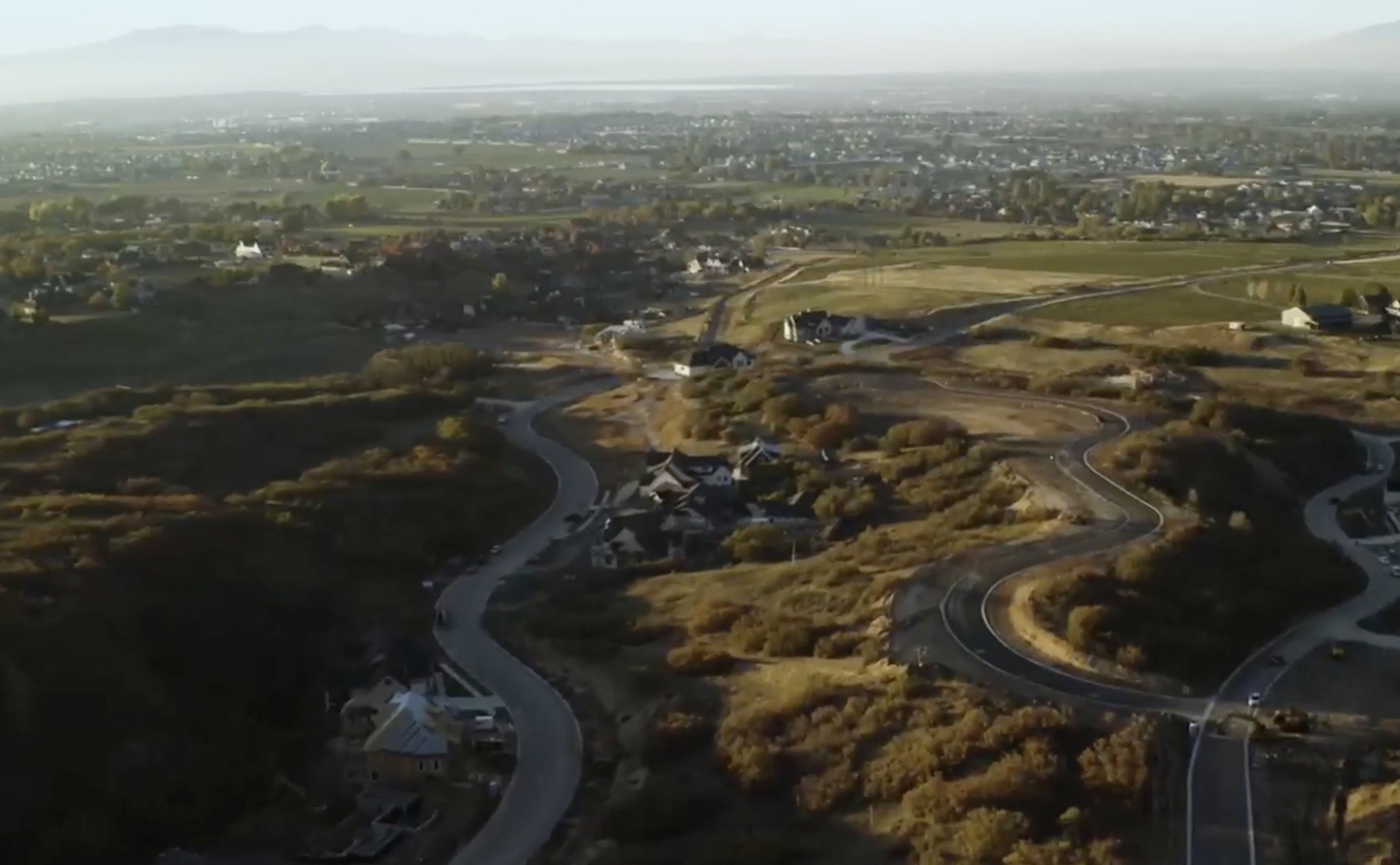 Winding roads traverse a developing residential area with established homes and new construction