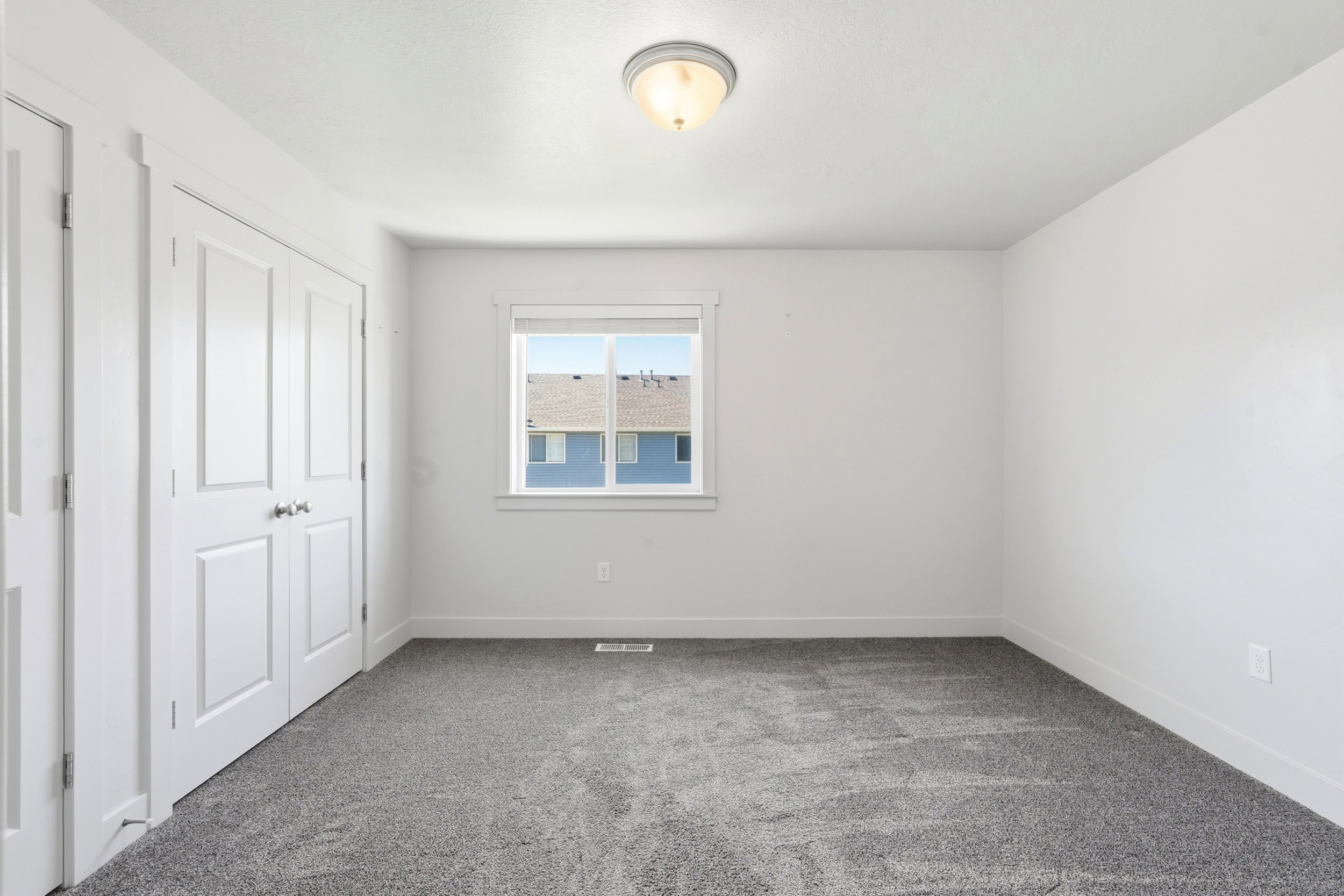 Neutral-toned room featuring a double-door closet, a single window, and grey patterned carpeting
