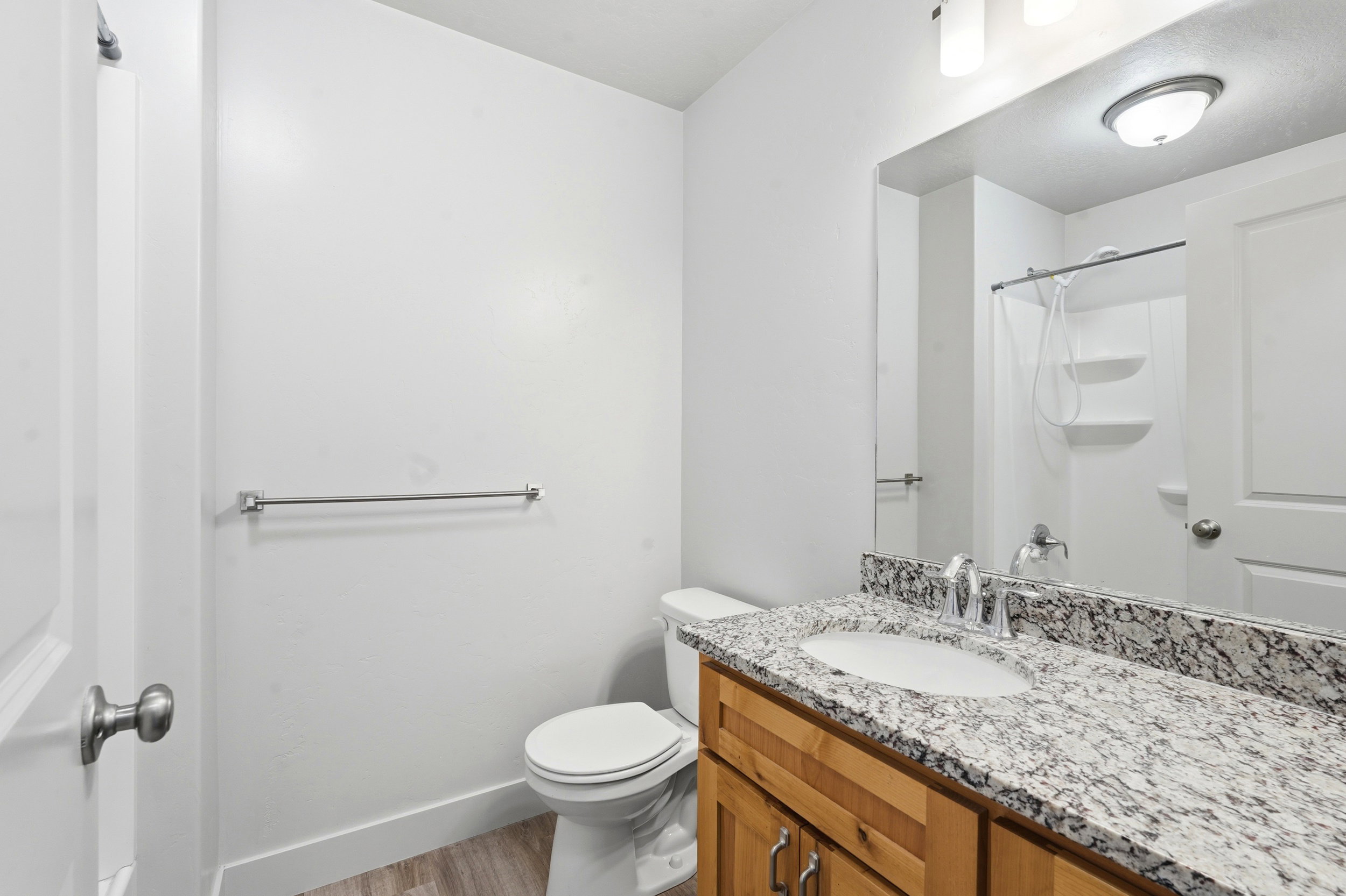 Bathroom featuring a wood-finish vanity with a light speckled countertop and undermount sink