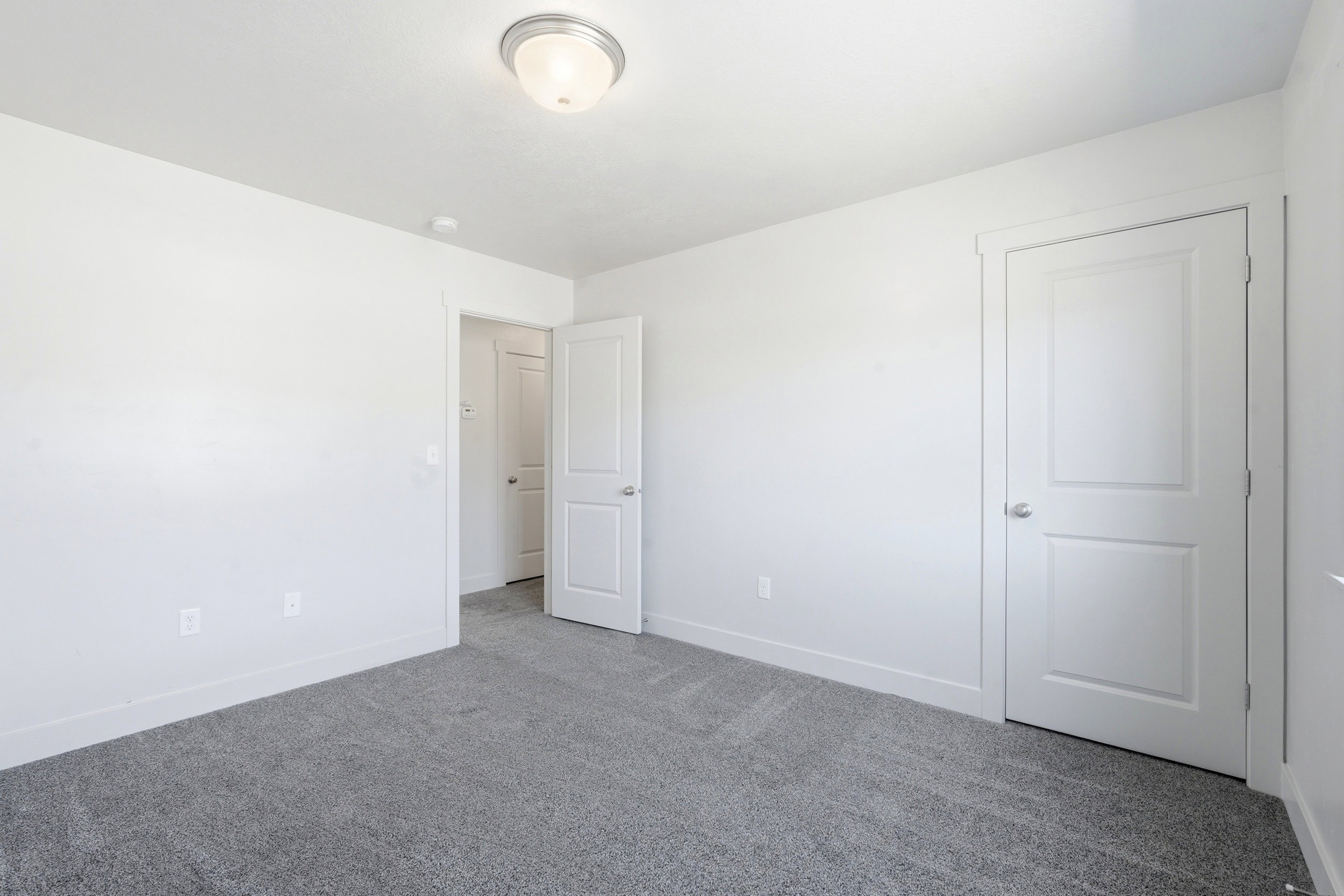 Neutral toned room featuring gray carpeting, white walls, and white trim