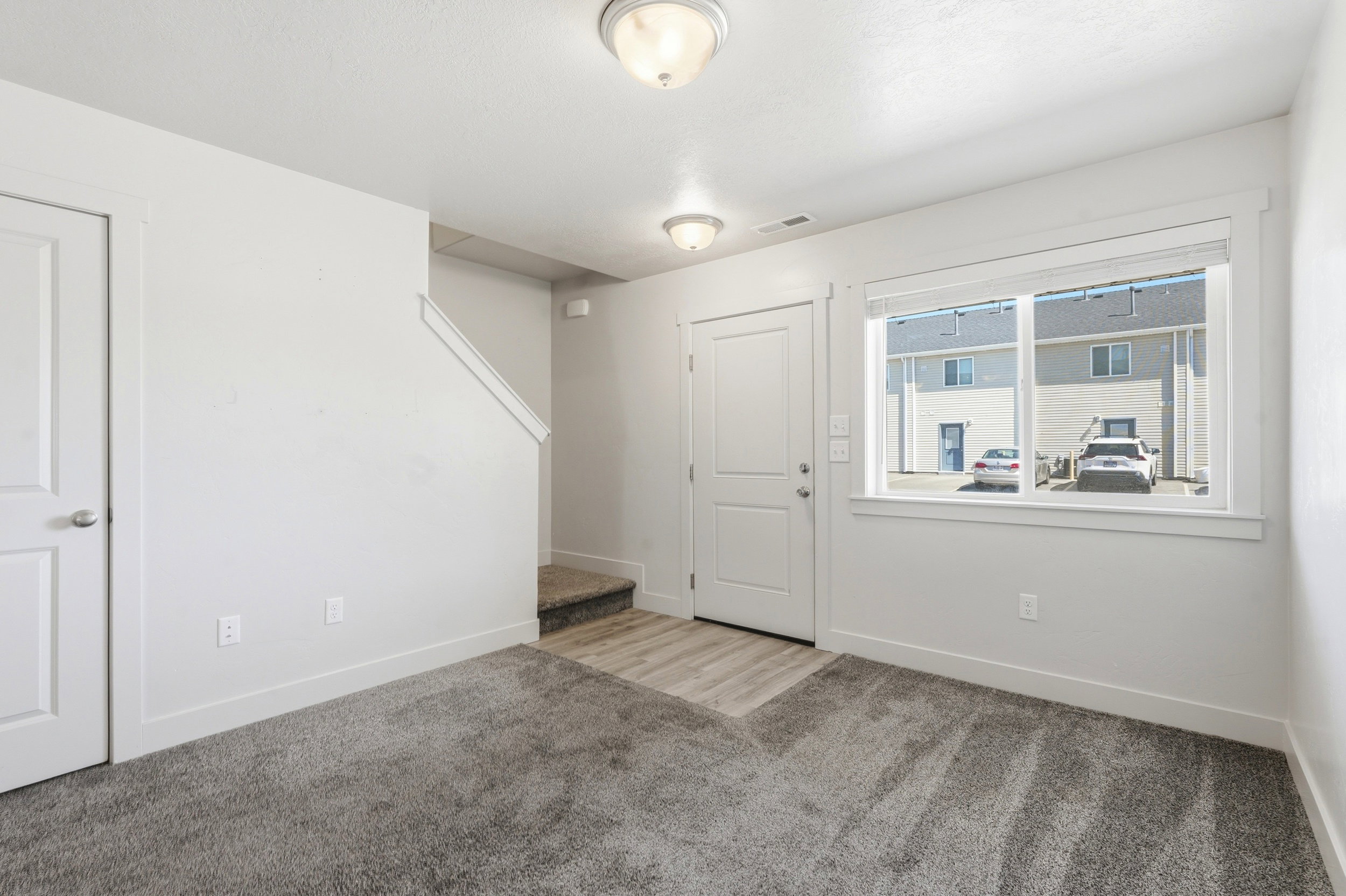 Entryway featuring wood-finish flooring, two white panel doors, and a staircase with carpeted treads