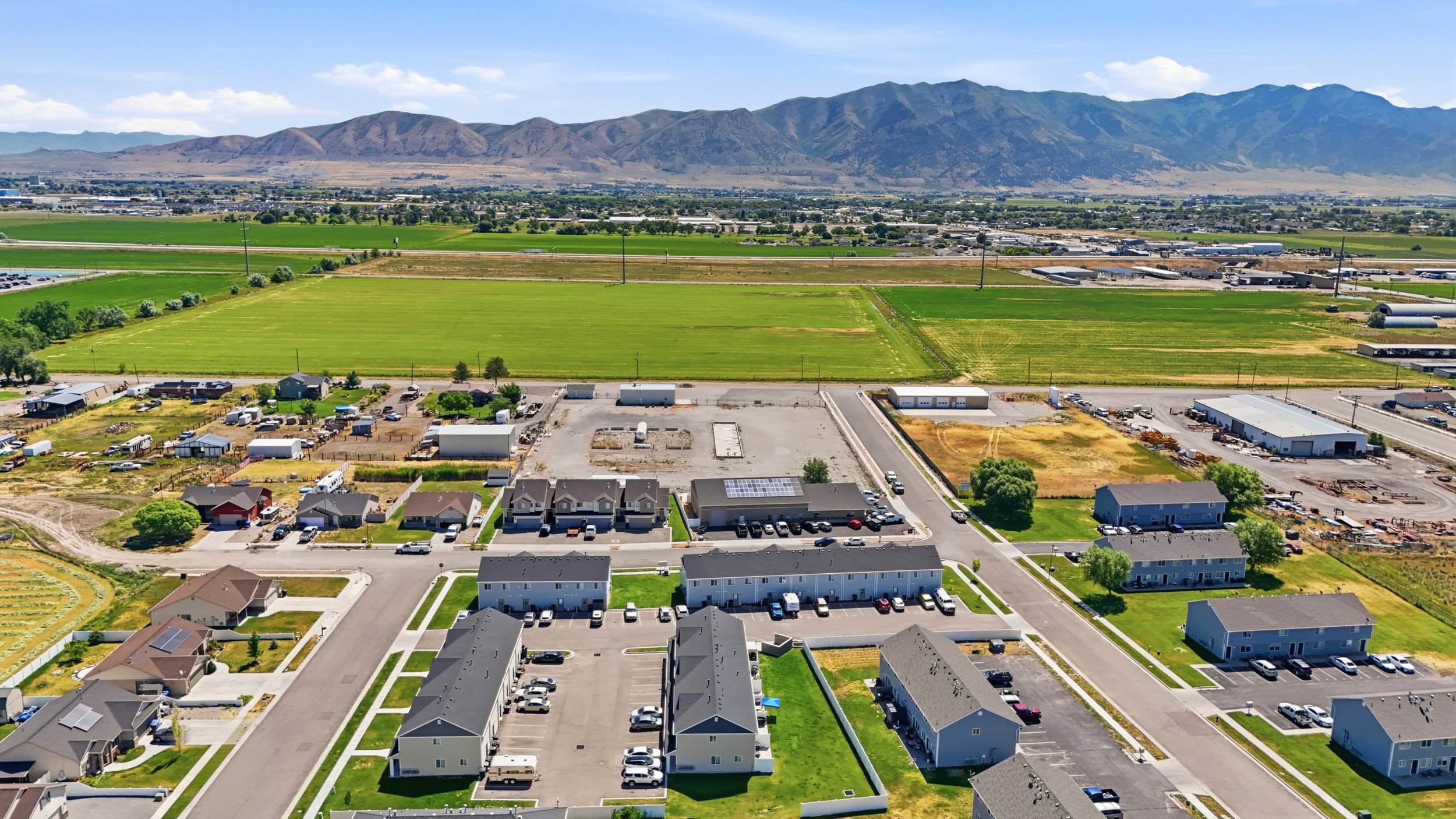 Aerial perspective showcasing a residential area with varied housing types, paved roadways, and green spaces