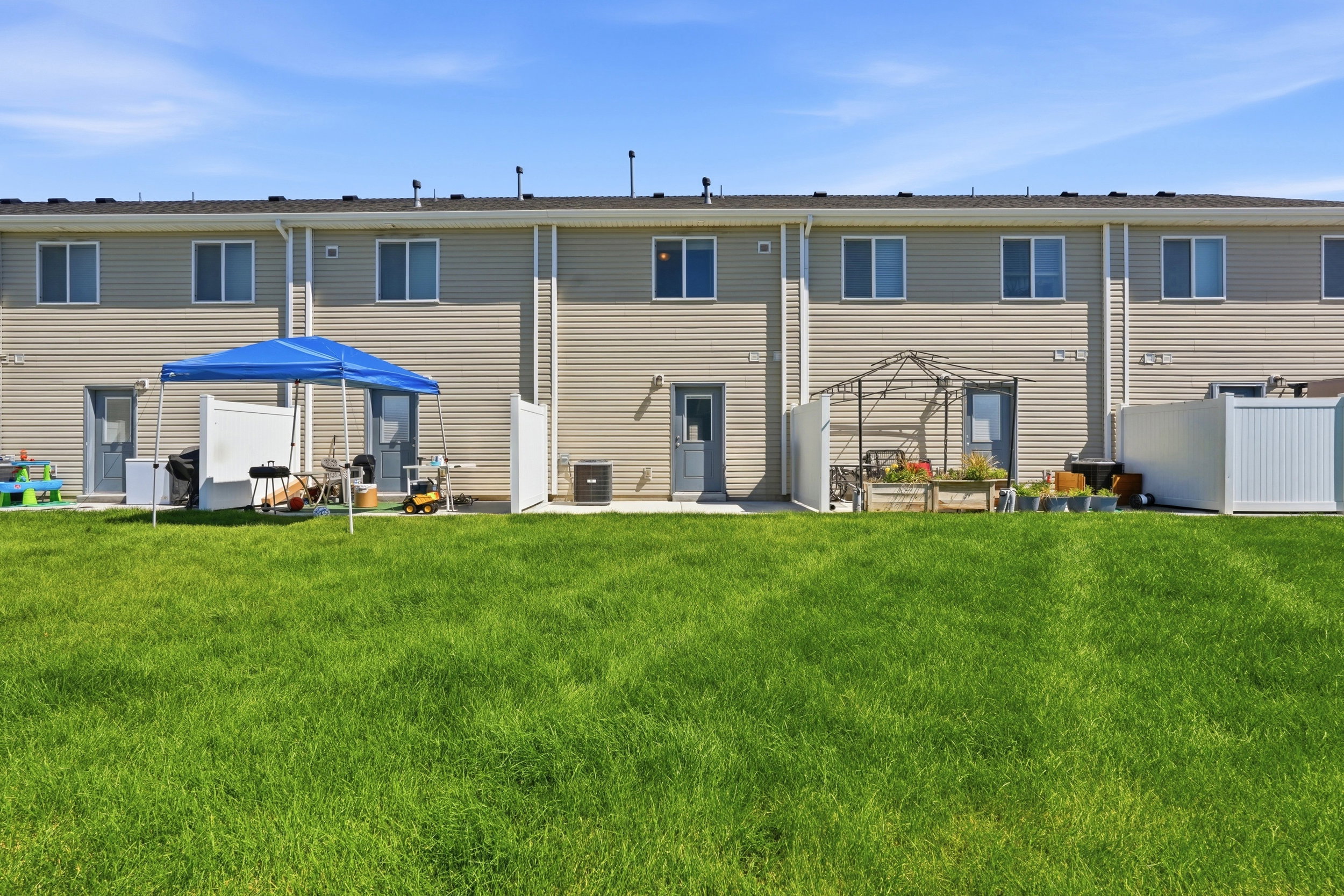 Expansive green lawn with rear building elevation featuring beige horizontal siding