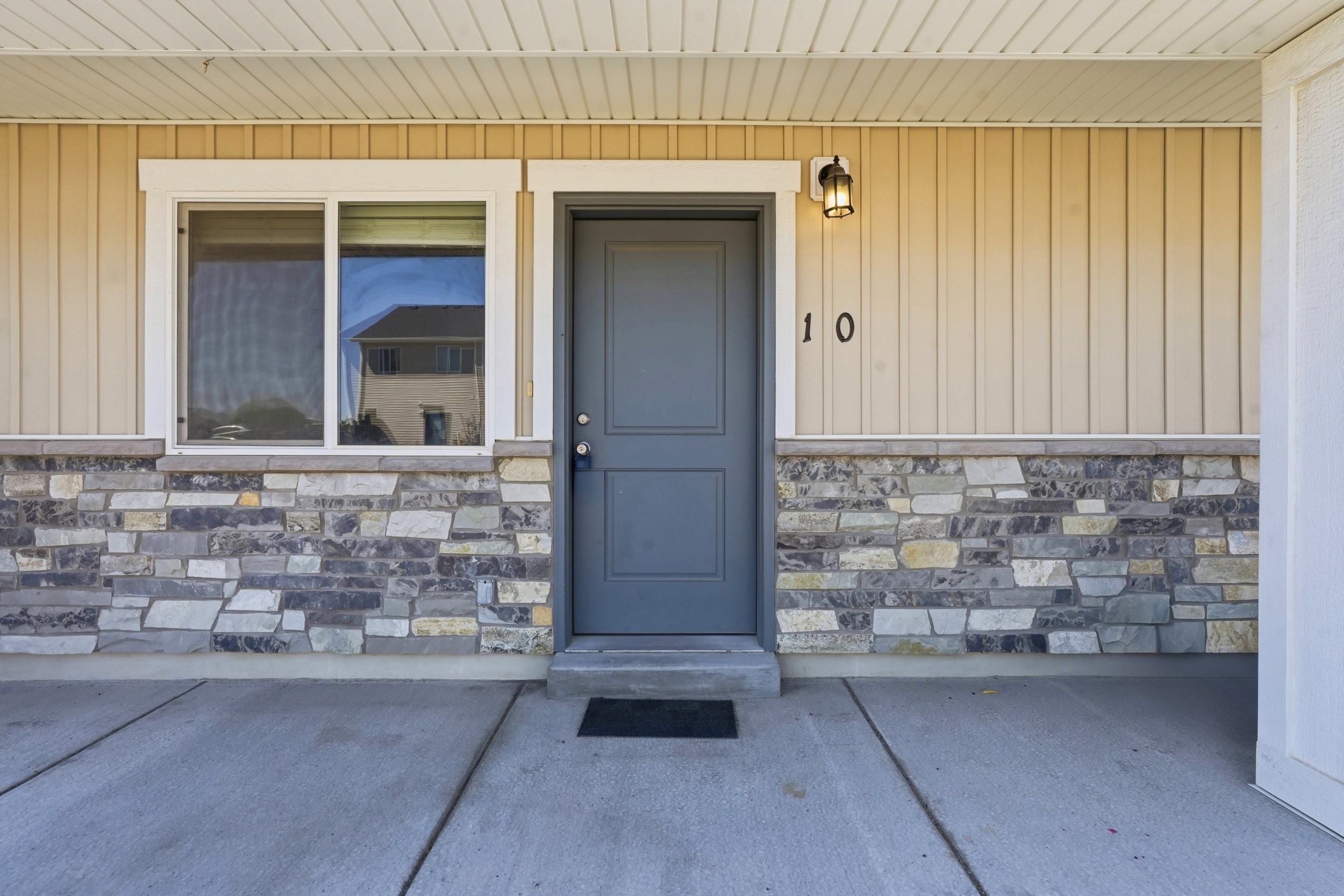 Front exterior showcasing stacked stone accents, vertical panel siding, and a contrasting gray entry door