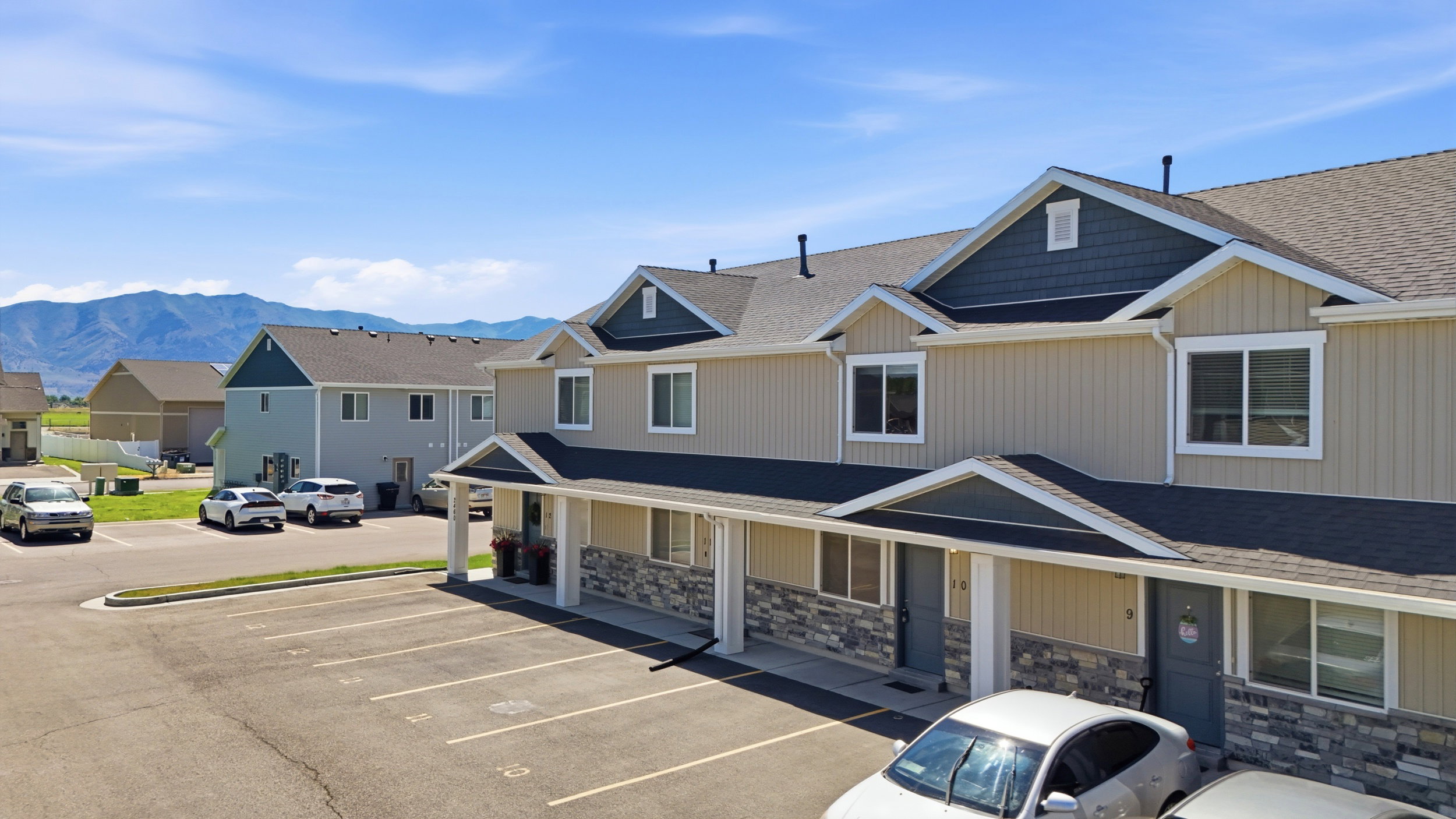 Multi-unit property featuring tan vertical siding and dark gray shingle roofing