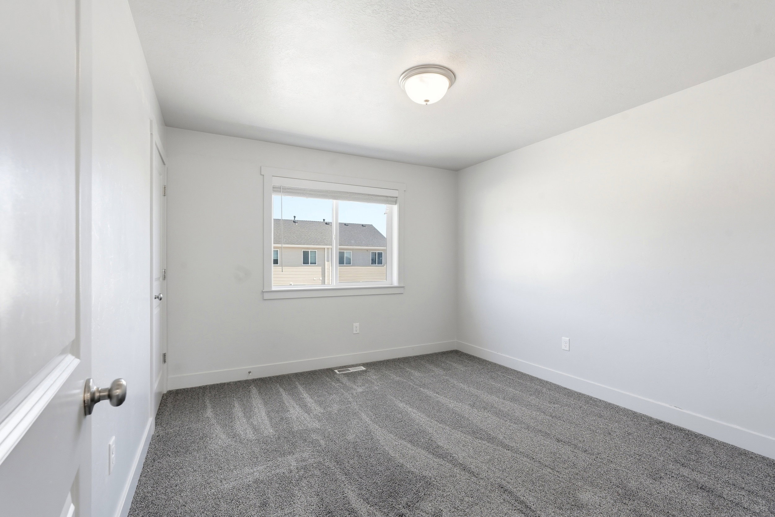Room featuring neutral-toned walls, plush gray carpet, and a window with white trim