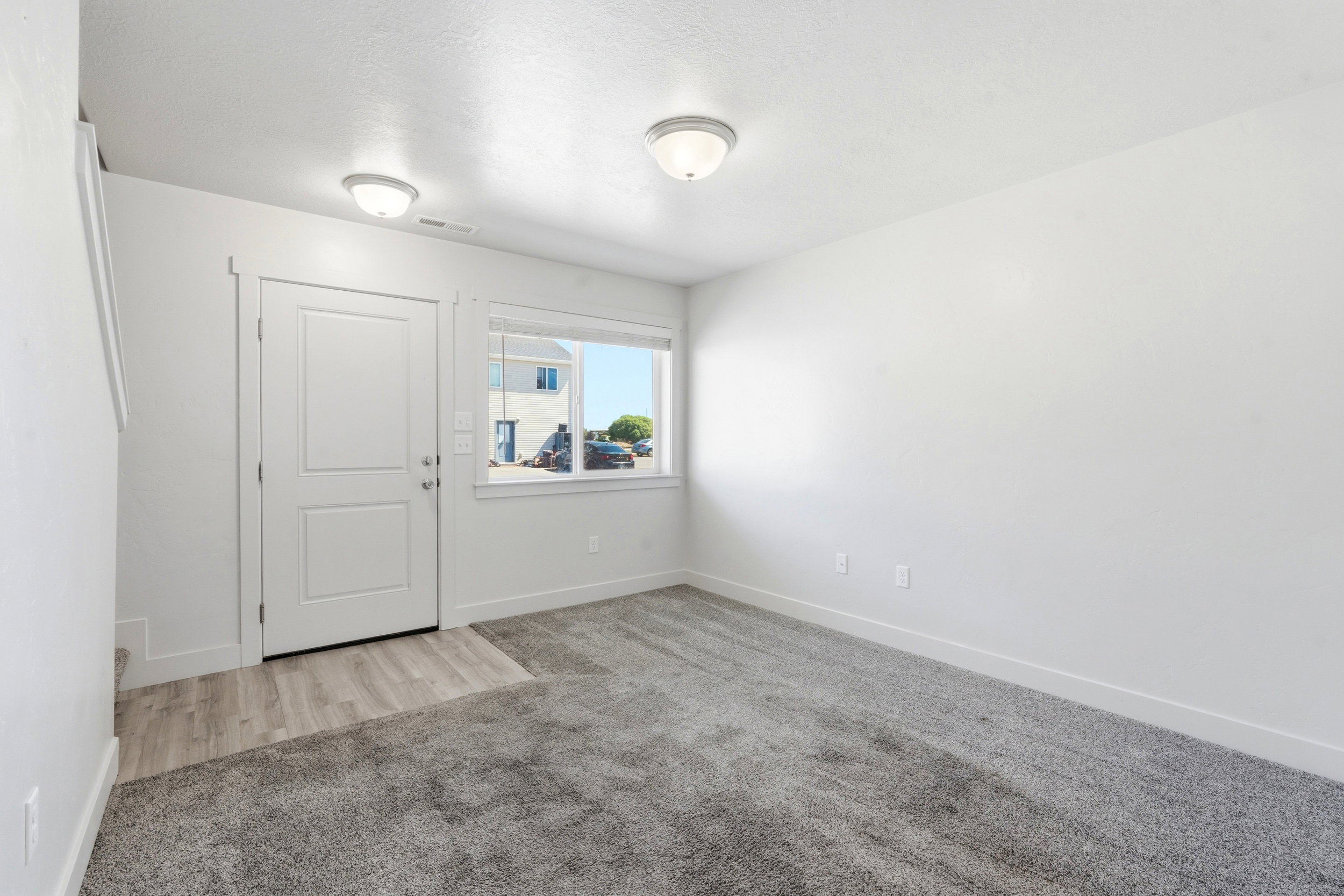 Entryway featuring a white paneled door, wood-finish flooring, and a large window