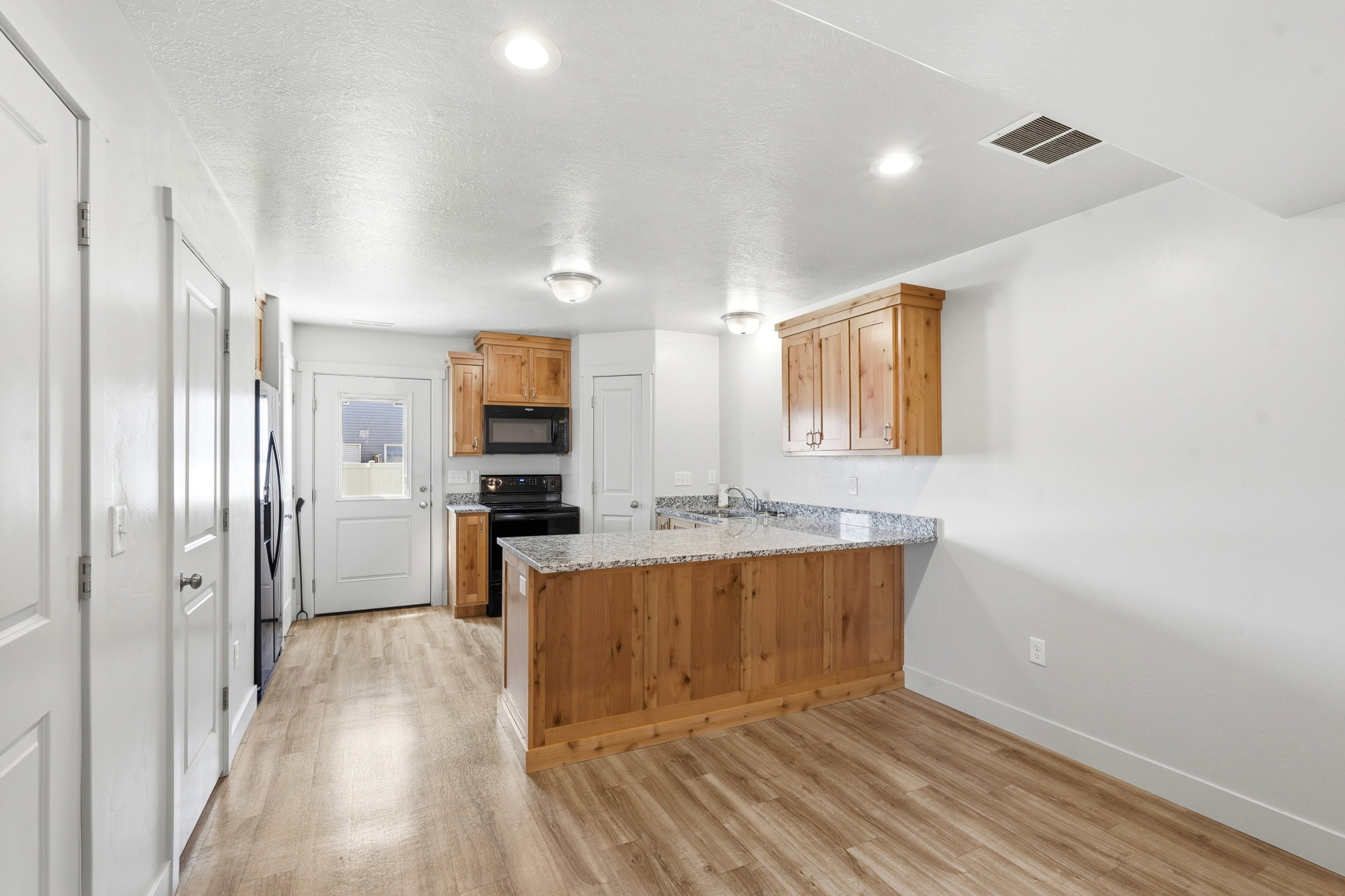 Kitchen featuring wood-finish flooring, recessed lighting, wood cabinetry, stone-finish countertops, and built-in appliances