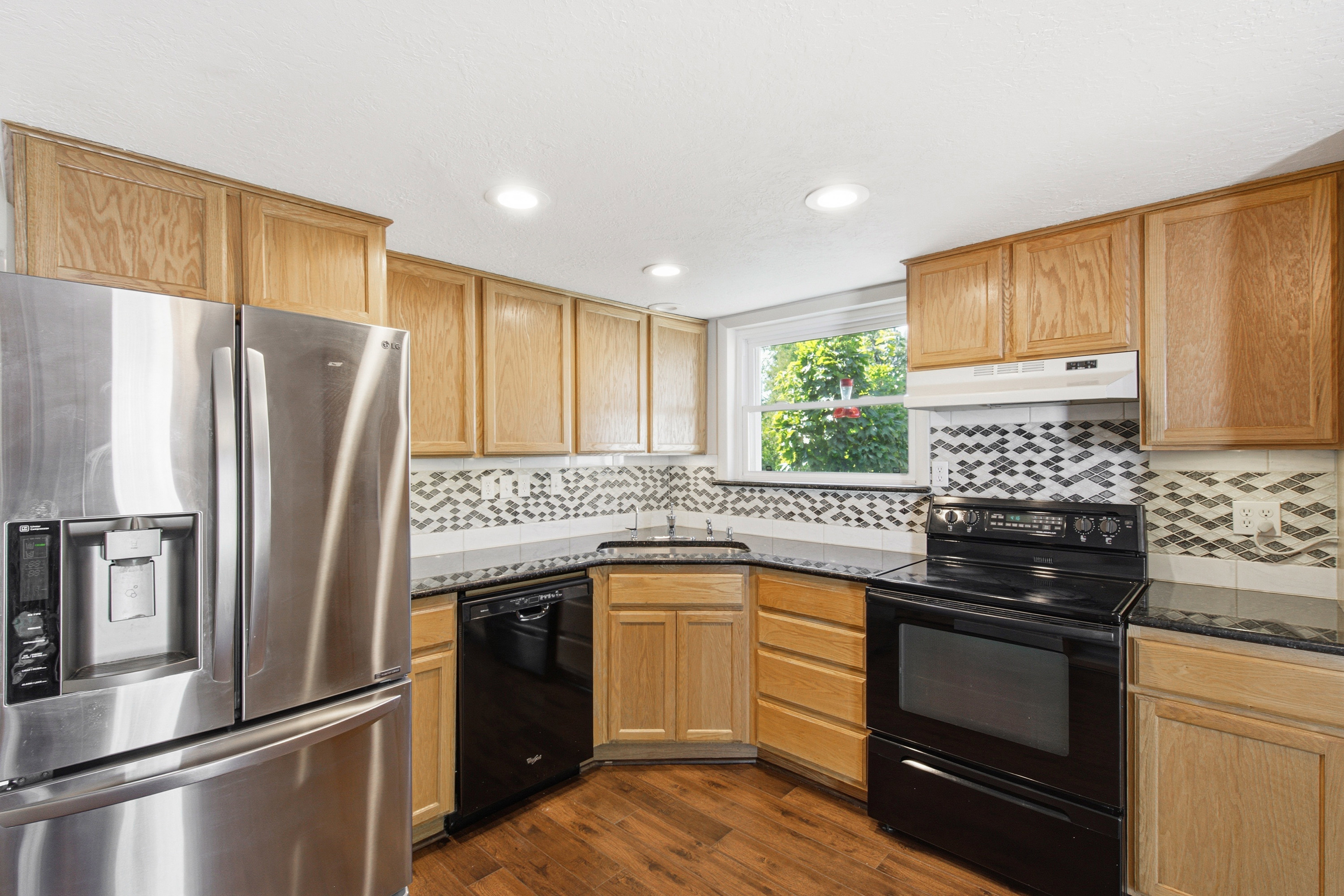 Kitchen featuring wood-finish flooring, recessed lighting, and light wood cabinetry with dark countertops