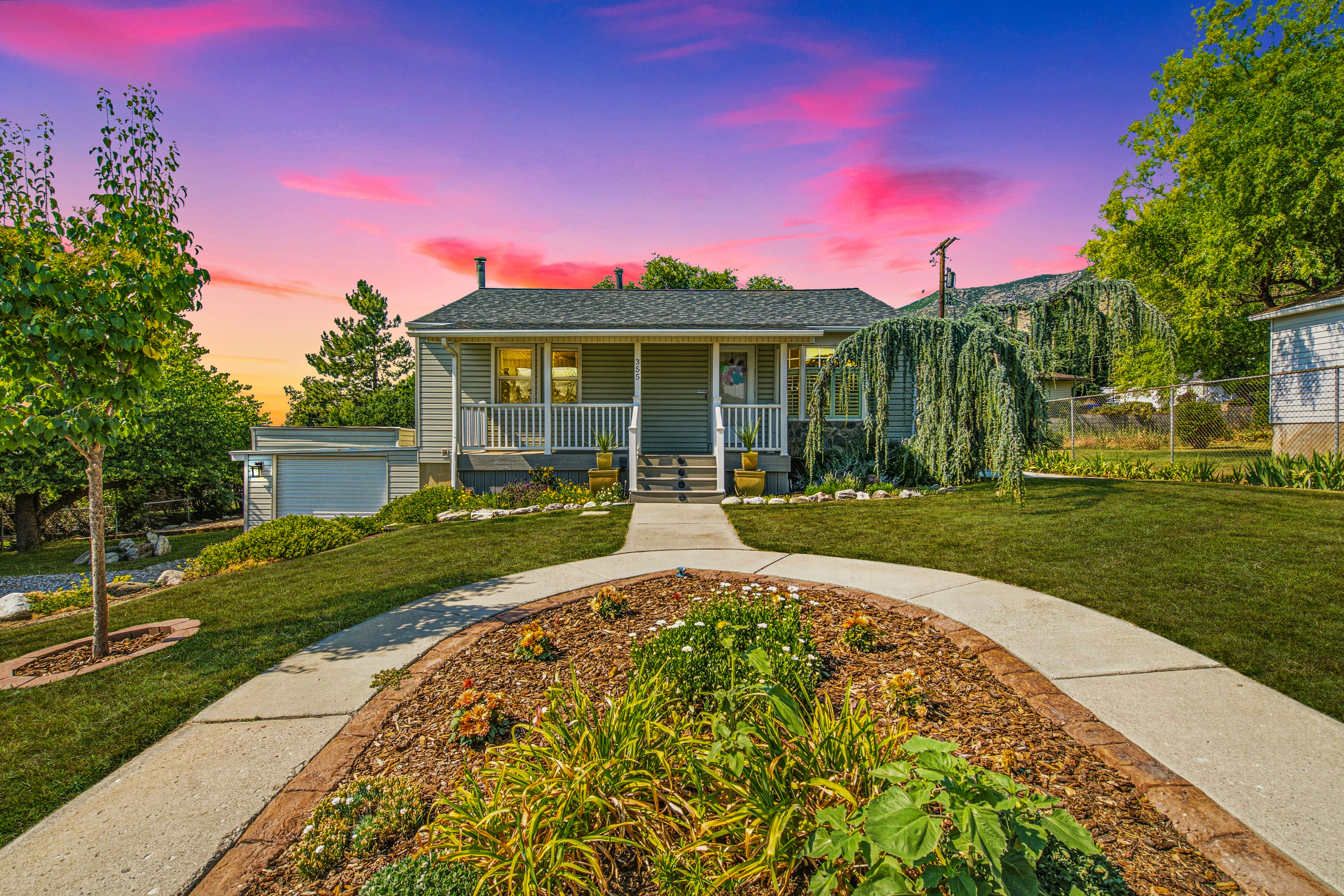 Crafted landscaping with a curved concrete pathway leading to the inviting front porch