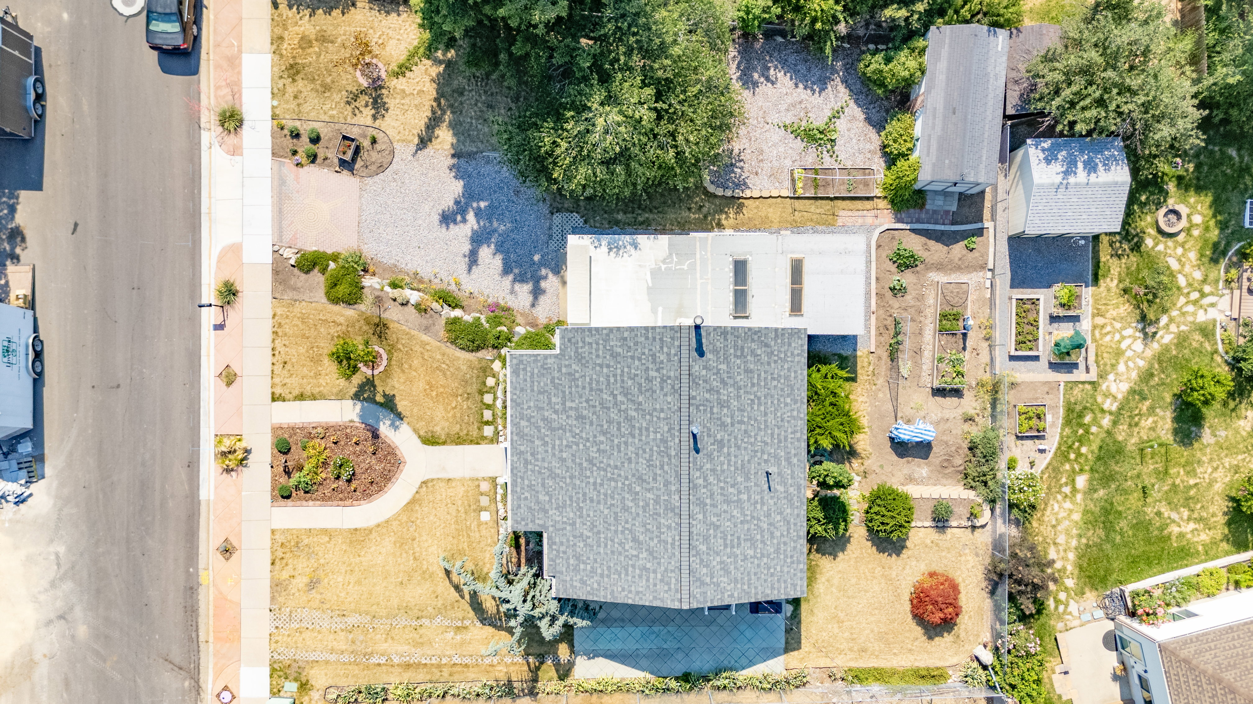 Aerial overview showcasing the property with a gray shingle roof, paved driveway, and established landscaping