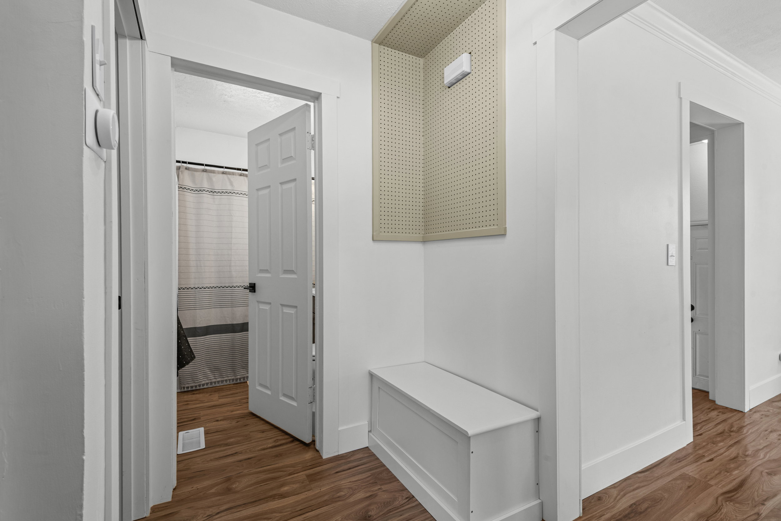 Hallway featuring wood-finish flooring, white walls, and white trim