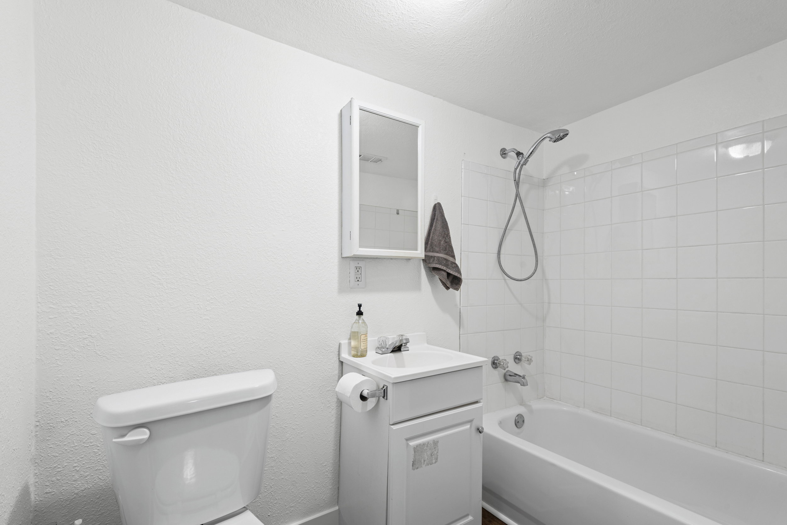 Bathroom featuring a white vanity with integrated sink, chrome faucet, and a wall-mounted medicine cabinet