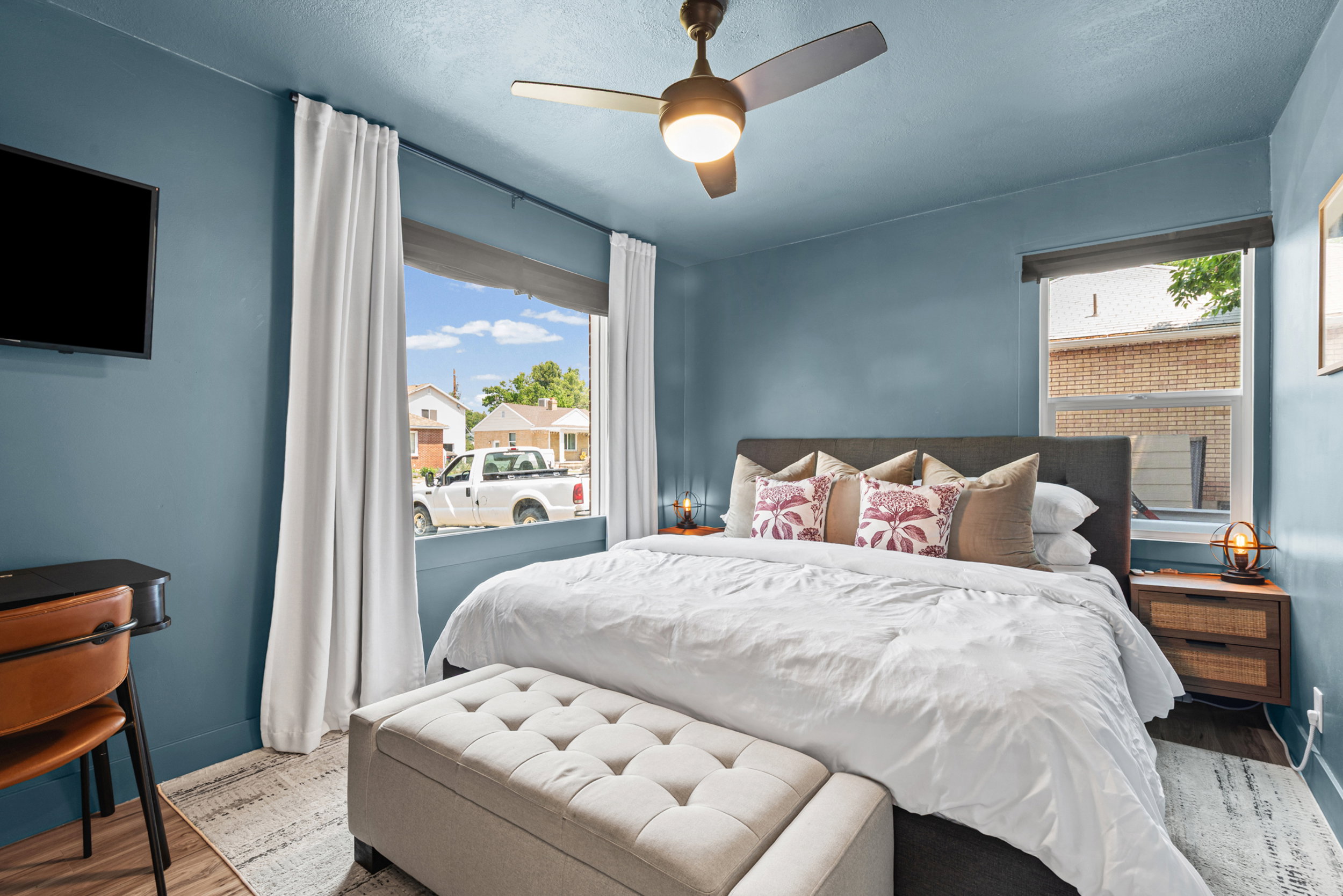 Bedroom featuring blue painted walls, wood-finish flooring, and a ceiling fan with integrated lighting