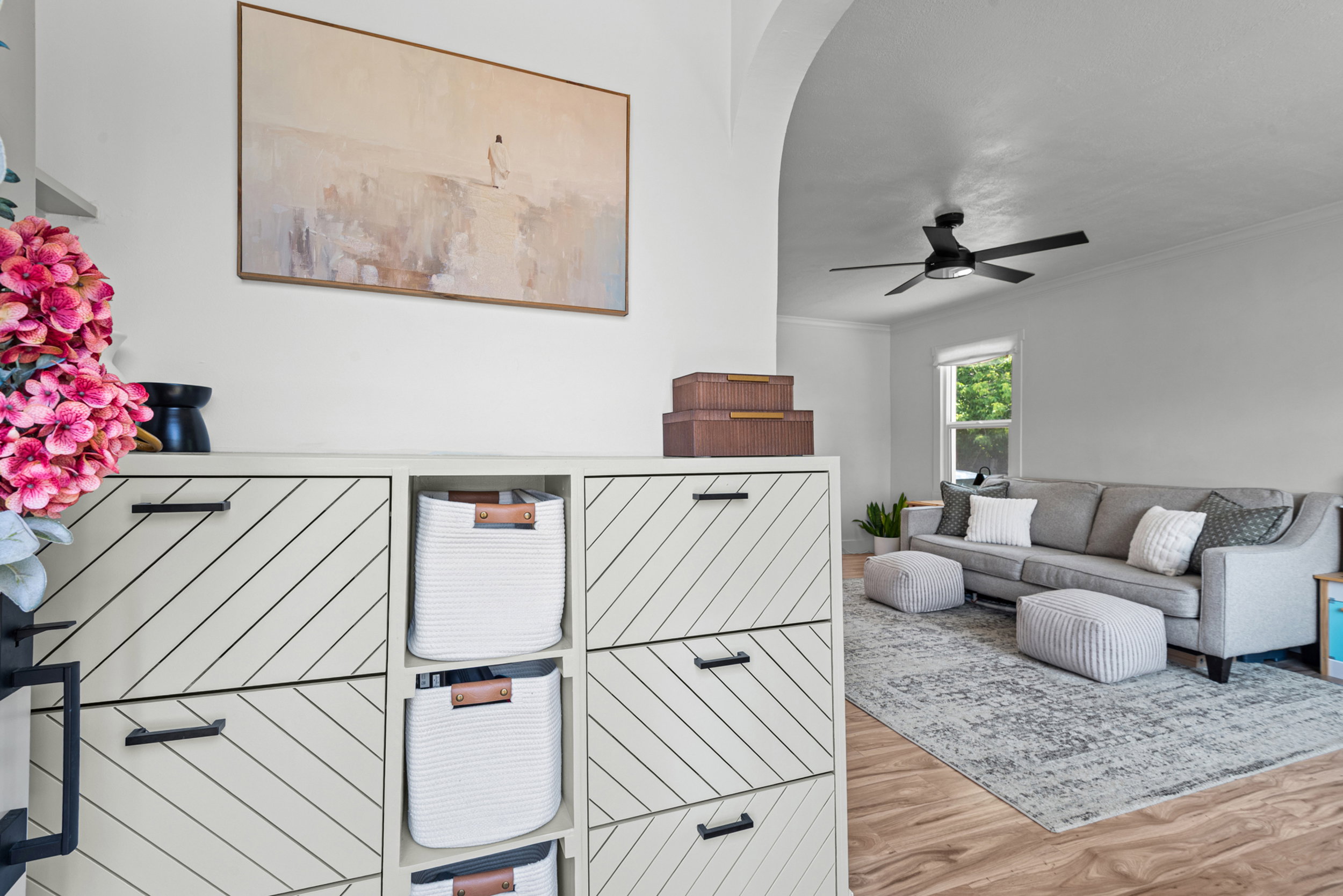 Archway entry into a living area featuring wood-finish flooring, white walls, and a ceiling fan
