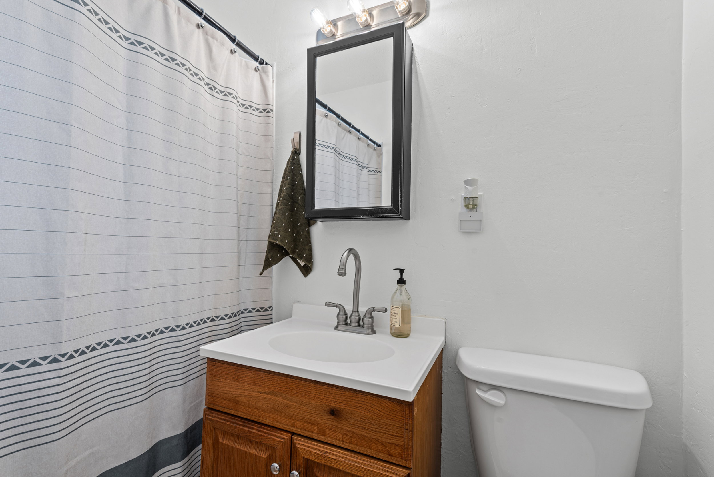 Bathroom vanity featuring a wood-finish cabinet, white countertop, and integrated sink