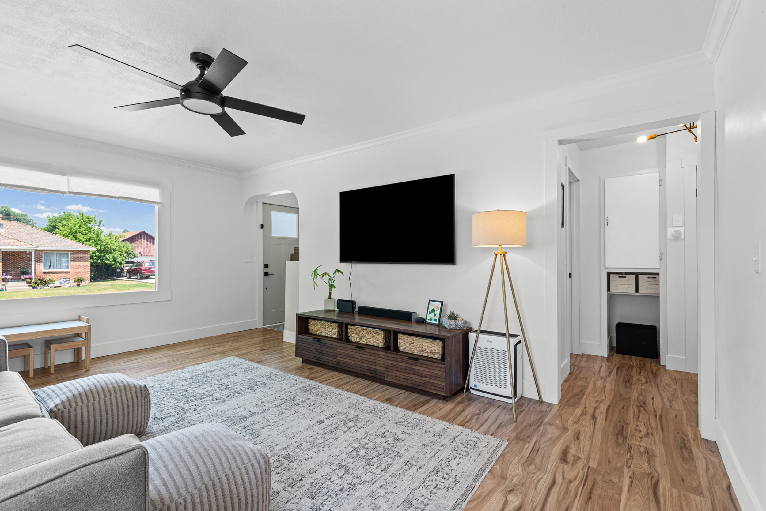 Bright living area with wood-finish flooring, a contemporary ceiling fan, and crown molding